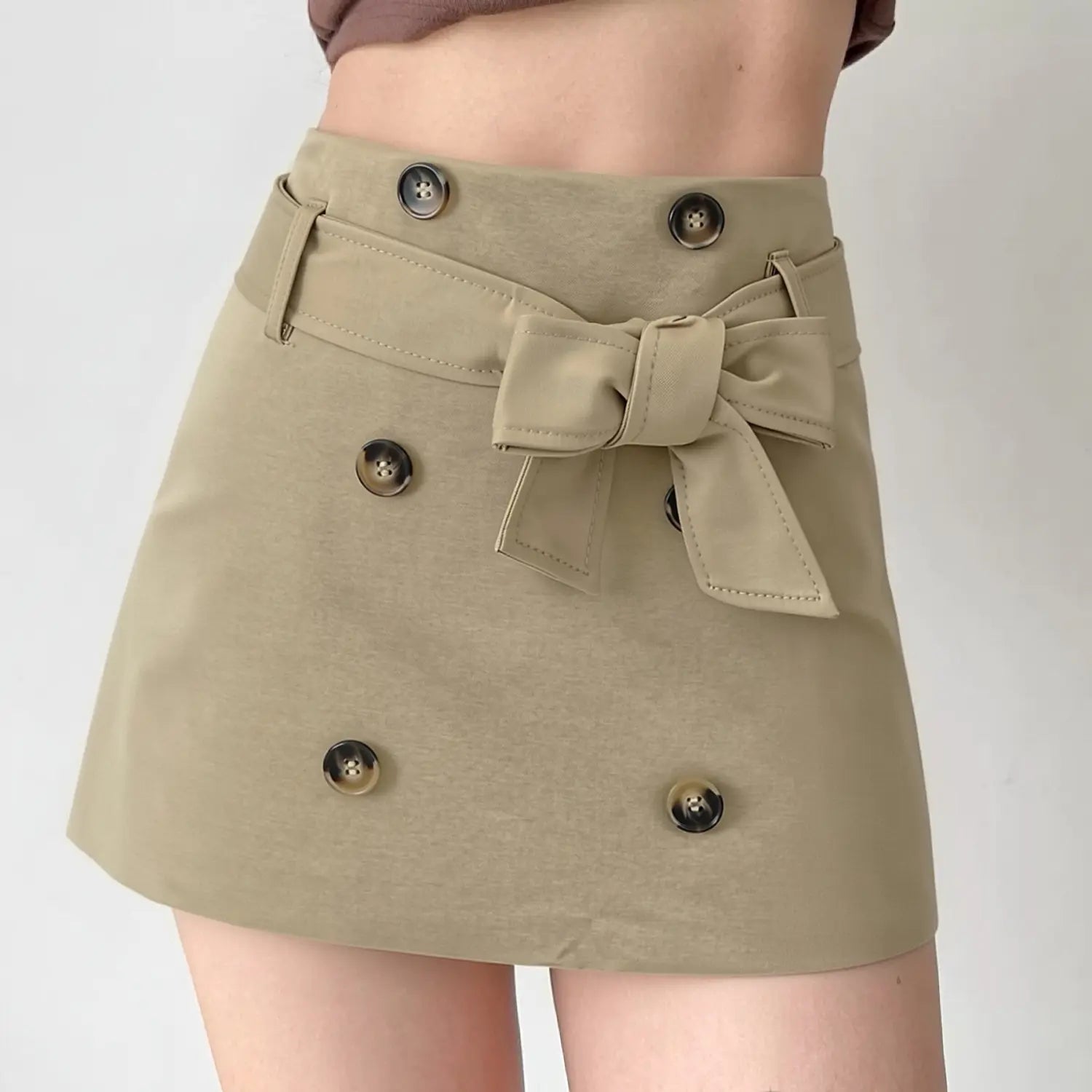Khaki bow tie belt a-line mini skirt half body indoor model shot, high waist leg-lengthening cut double decorative buttons 3D bow design matched with cropped top commuter sweet girl daily outfit display