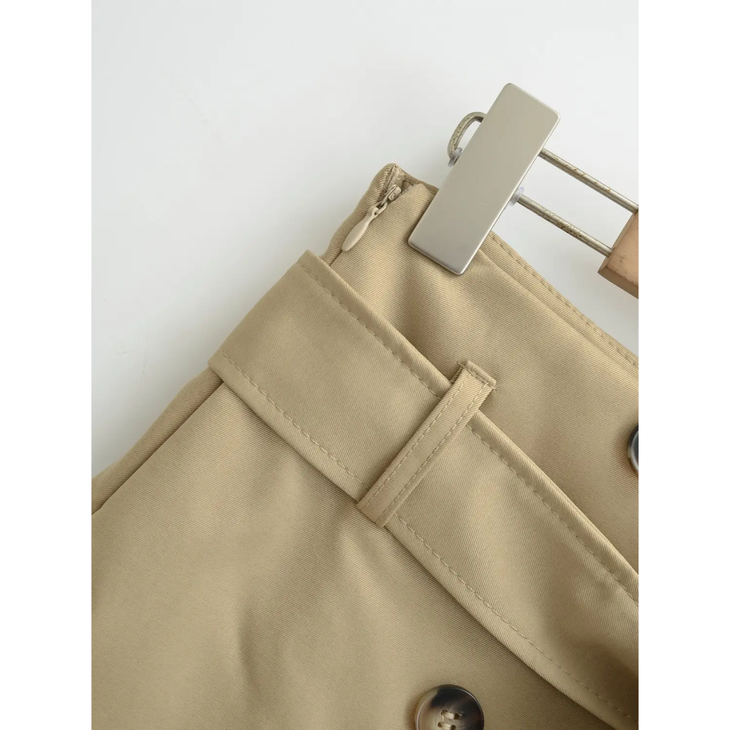 Khaki a-line mini skirt side waist flat close-up, side invisible smooth zipper reinforced belt loops double line binding waistband twill fabric white background craft shot