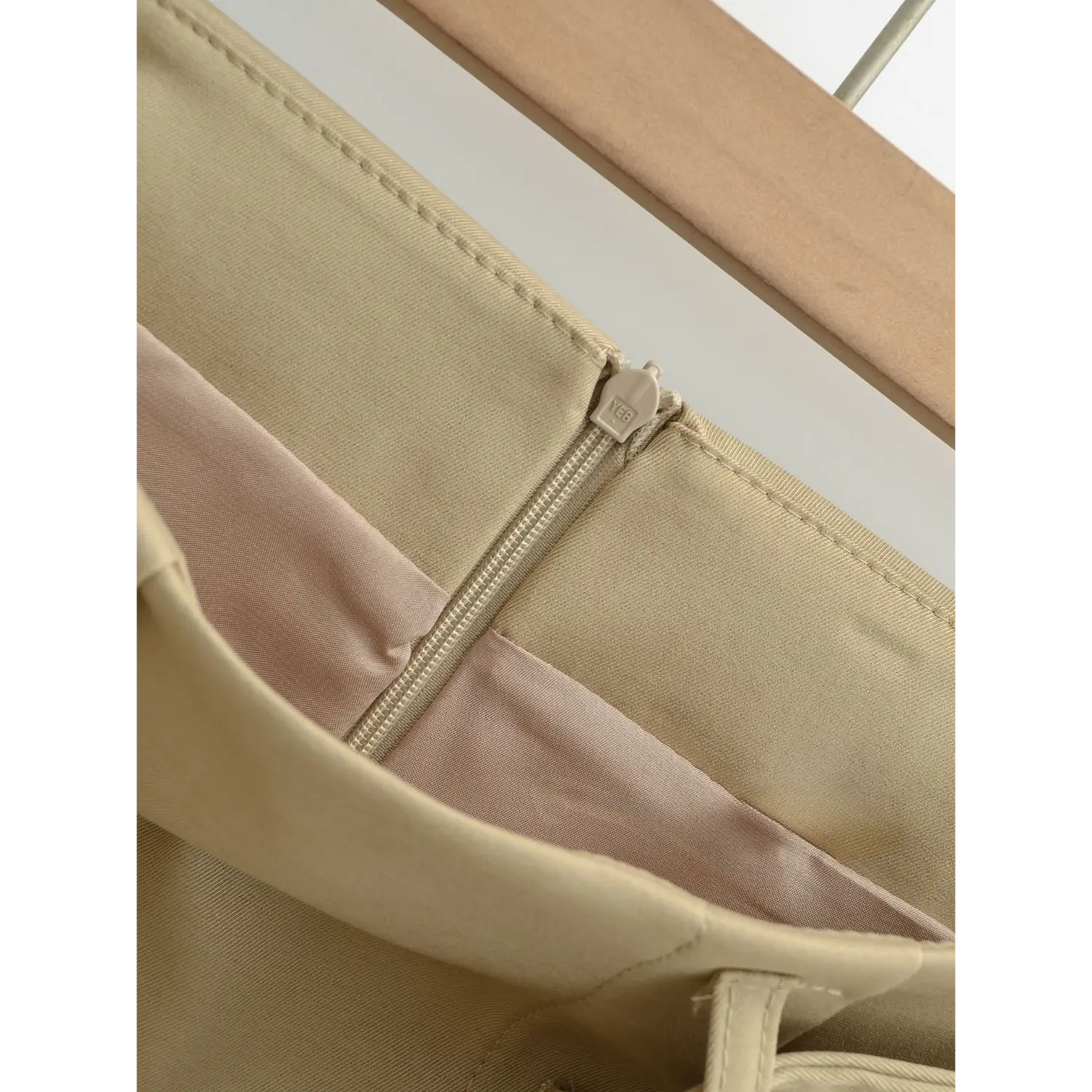 Khaki a-line mini skirt zipper inner lining macro flat close-up, light pink smooth anti-exposure lining full overlock around zipper neat twill outer splice white background shot