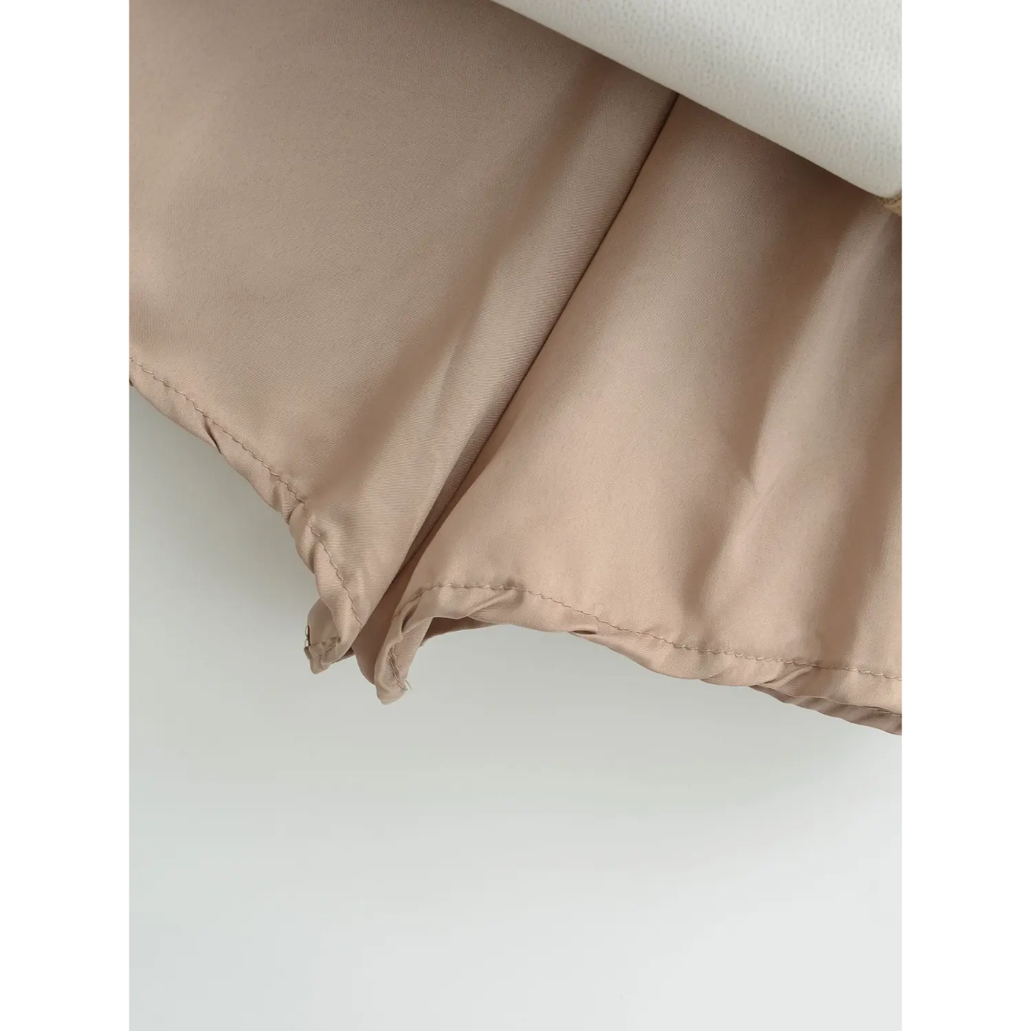 Khaki work skirt inner lining hem flat close-up, light pink skin-friendly lining wavy elastic overlock full hem lining anti-chafing craft white background shot