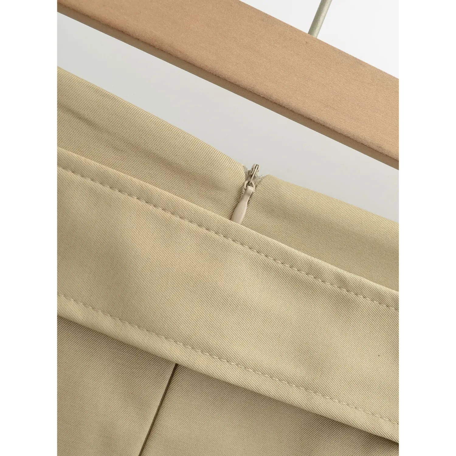 Khaki work mini skirt back waist invisible zipper outer flat close-up, double stitched waistband smooth matching hidden zipper fine stiff twill suit fabric white background craft shot