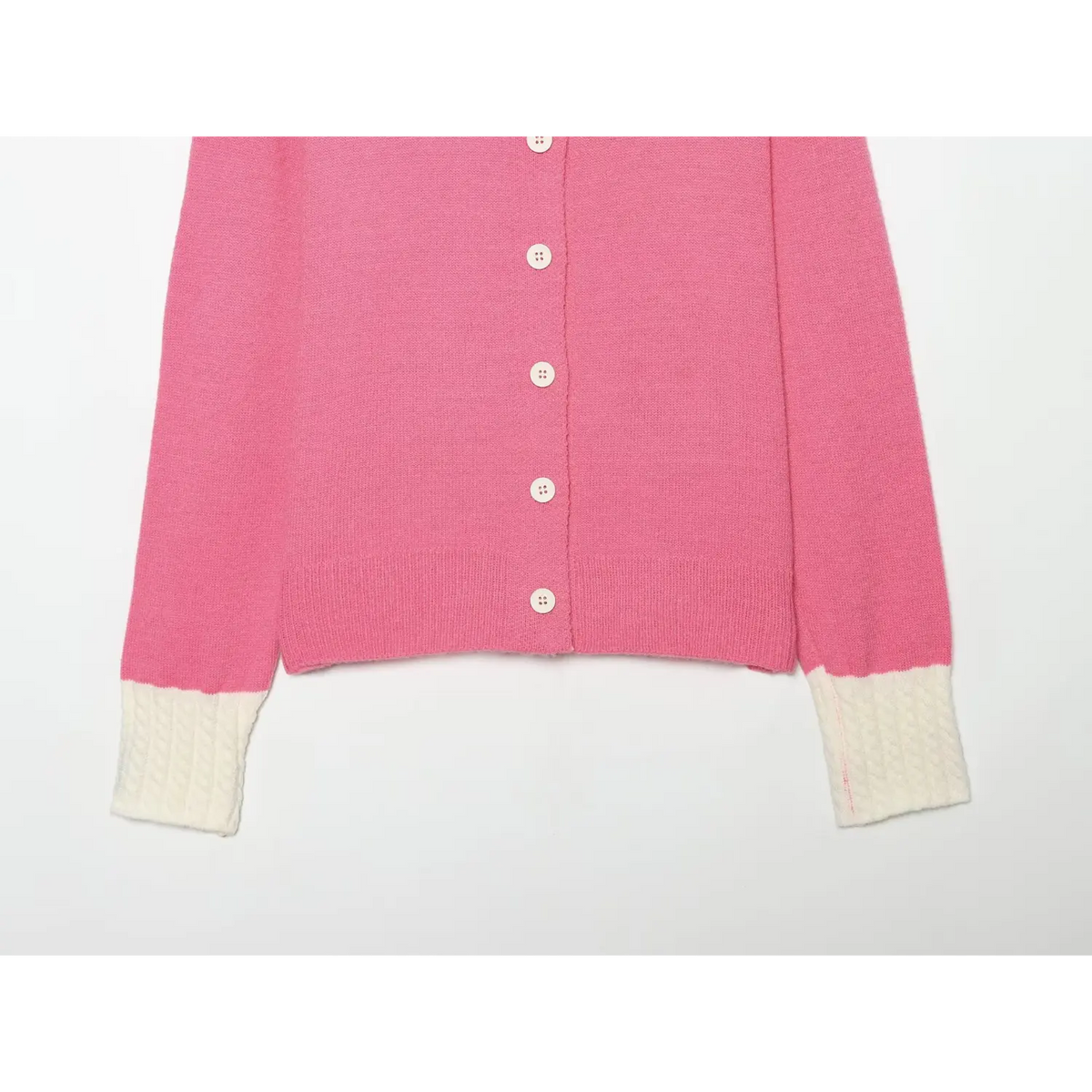Partial shot of pink cropped cardigan, long sleeves with white cable knit cuffs and ribbed hem