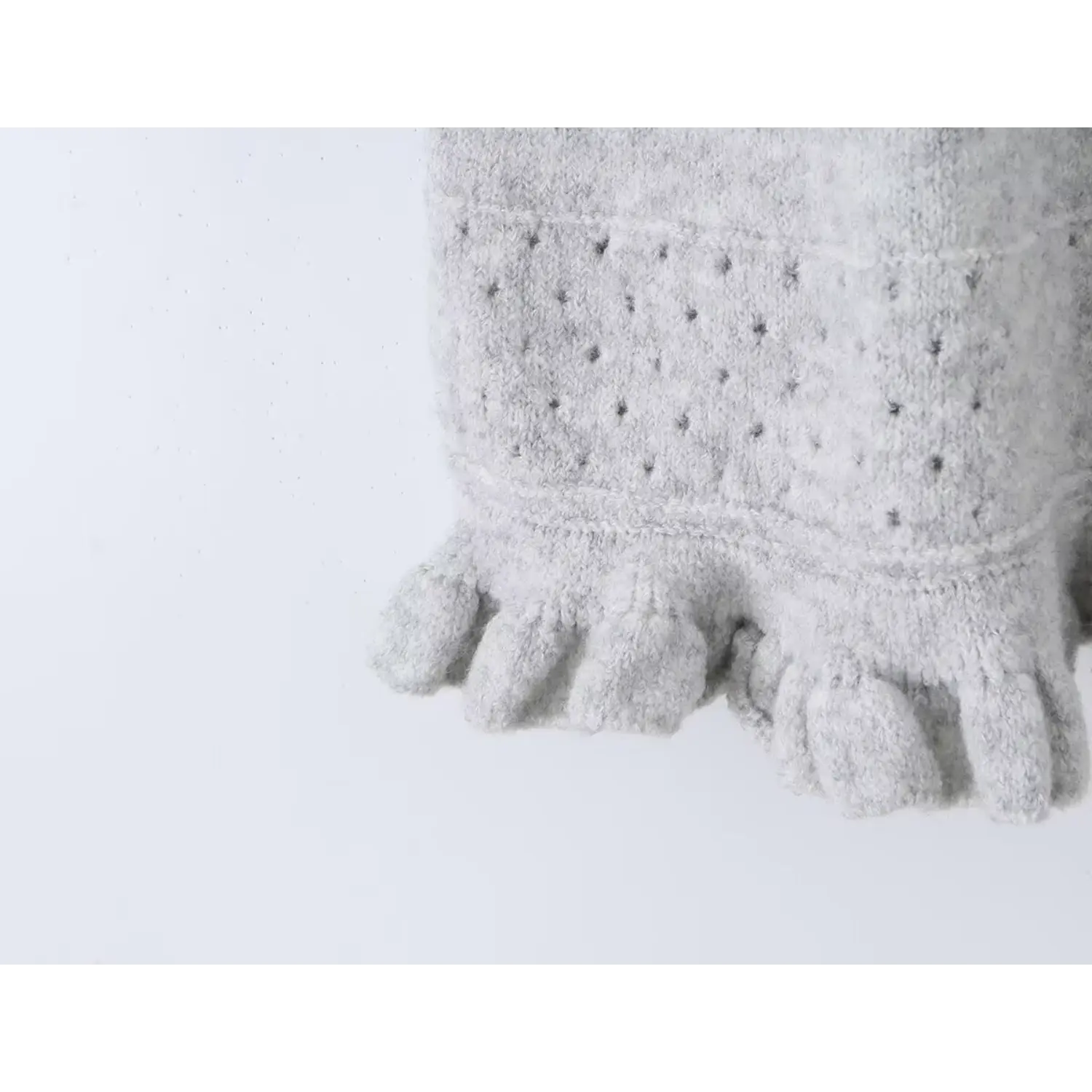 Macro detail of hollow dot knit band and multi-layer ruffle hem on grey mini knit dress