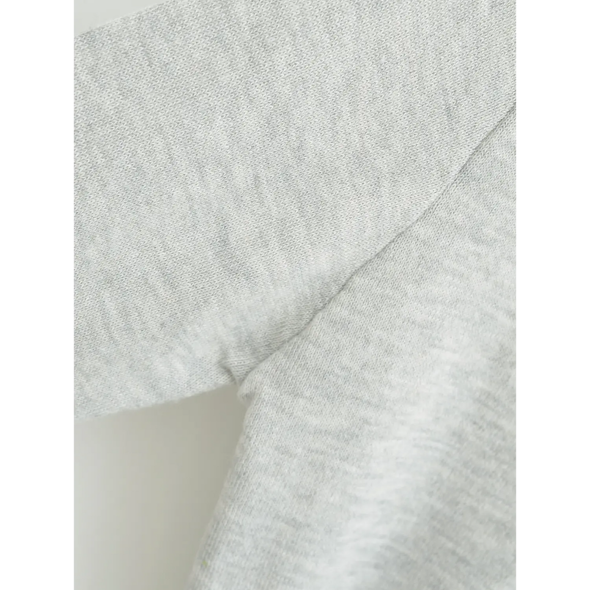 Fabric macro shot showing fine soft heather knit texture and shoulder seam construction