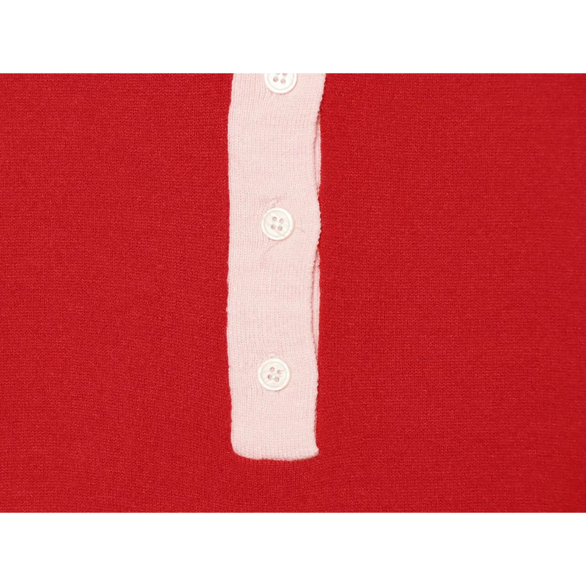 Close-up view of pink placket with white round buttons on red knit polo sweater