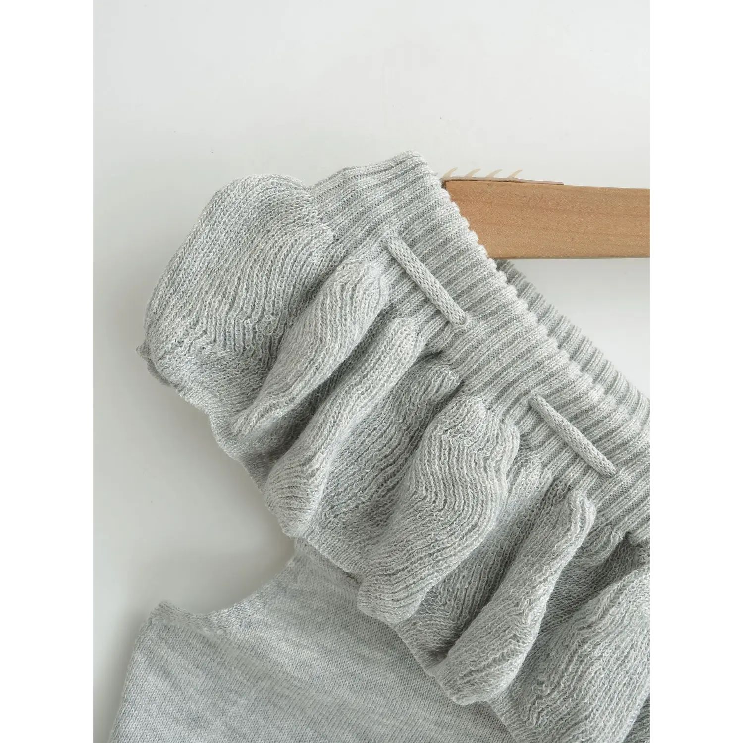 Knit tube top ruffle flounce rib neck macro flat close-up, fine stretch knit texture evenly gathered flounce neat stitched drawstring loops white background craft shot