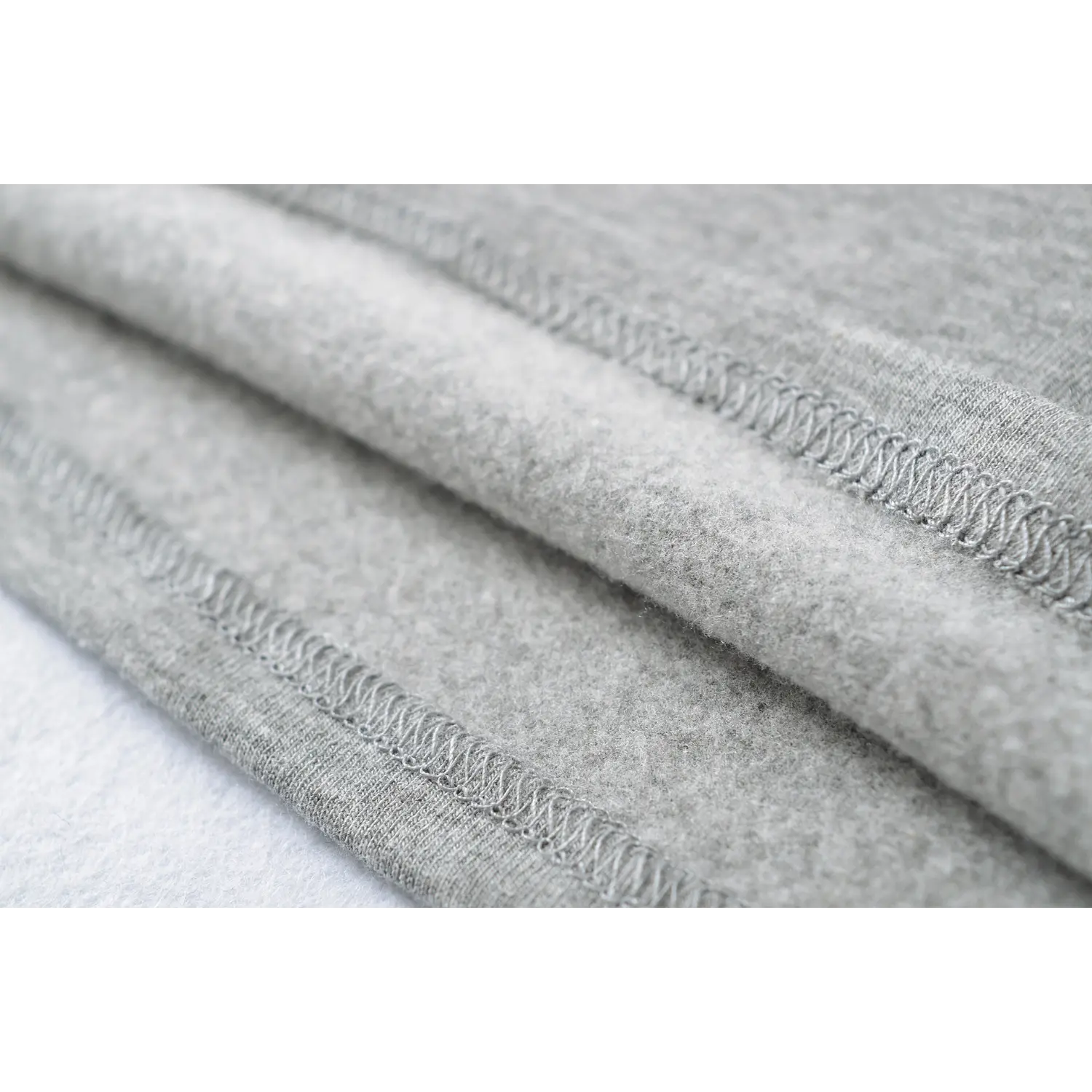 Knit tank side elastic overlock stitch macro flat close-up, uniform elastic serging anti-breakage fine sewing detail white shot