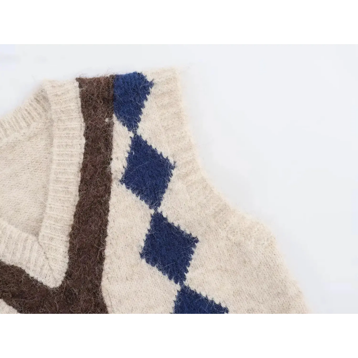 Close-up of armhole and side argyle pattern on cream fuzzy sleeveless knit vest