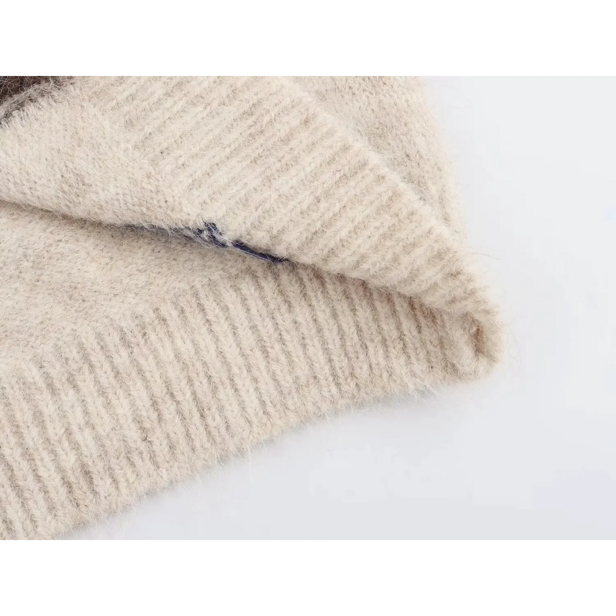Inner fabric close-up of cream fuzzy knit vest, soft fluffy knit texture and ribbed hem