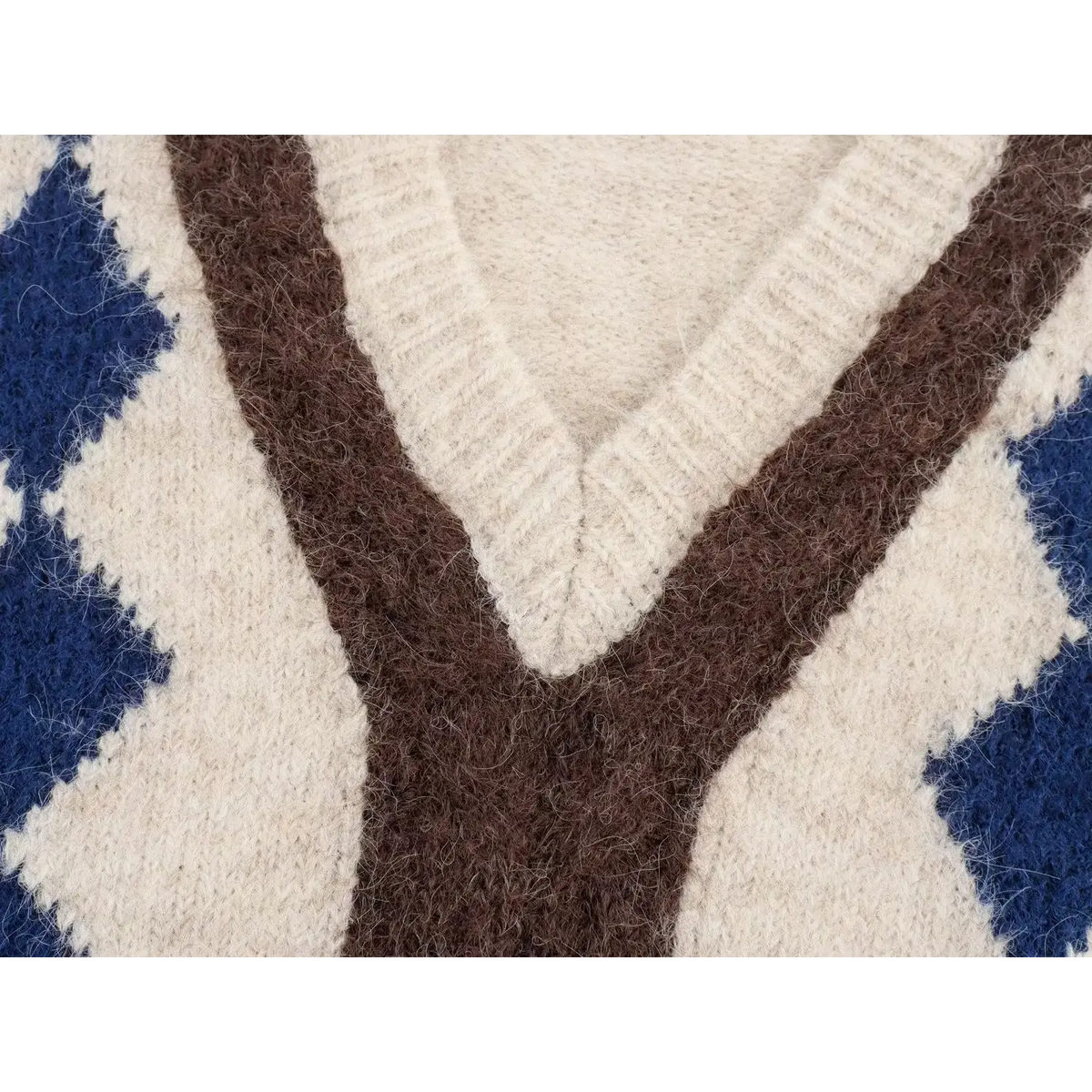 Close-up of v-neckline, brown Y jacquard and navy blue argyle diamond knit pattern