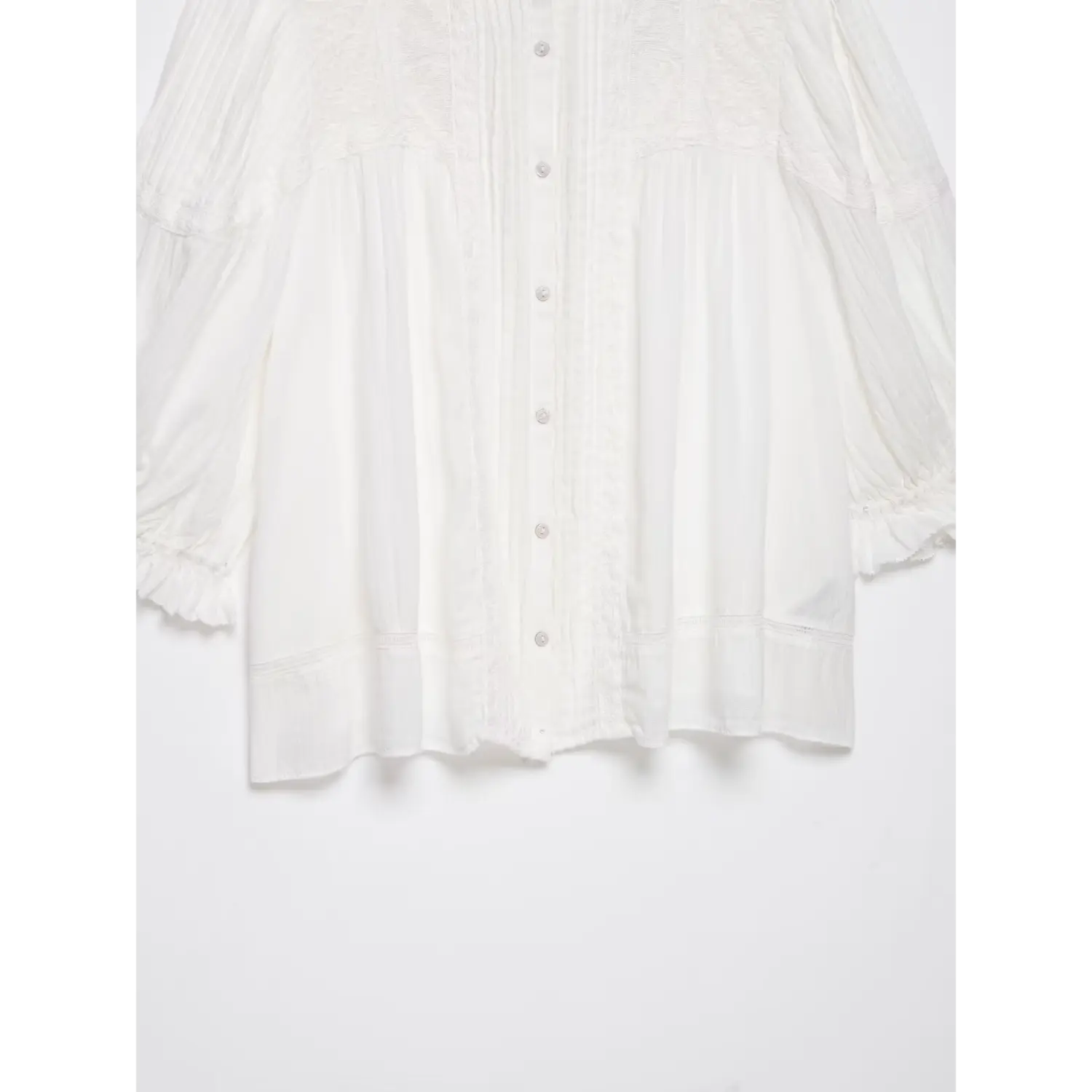 Partial shot of relaxed shirt hem, decorative ladder stitch trim and gathered waist silhouette