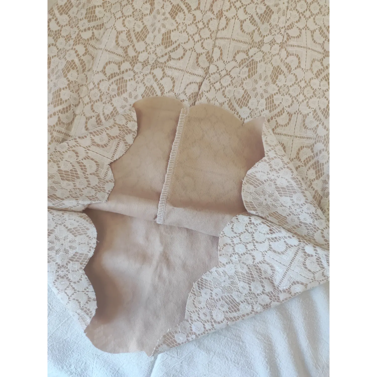 Close-up of dress hem, scalloped edge white lace with nude inner lining detail