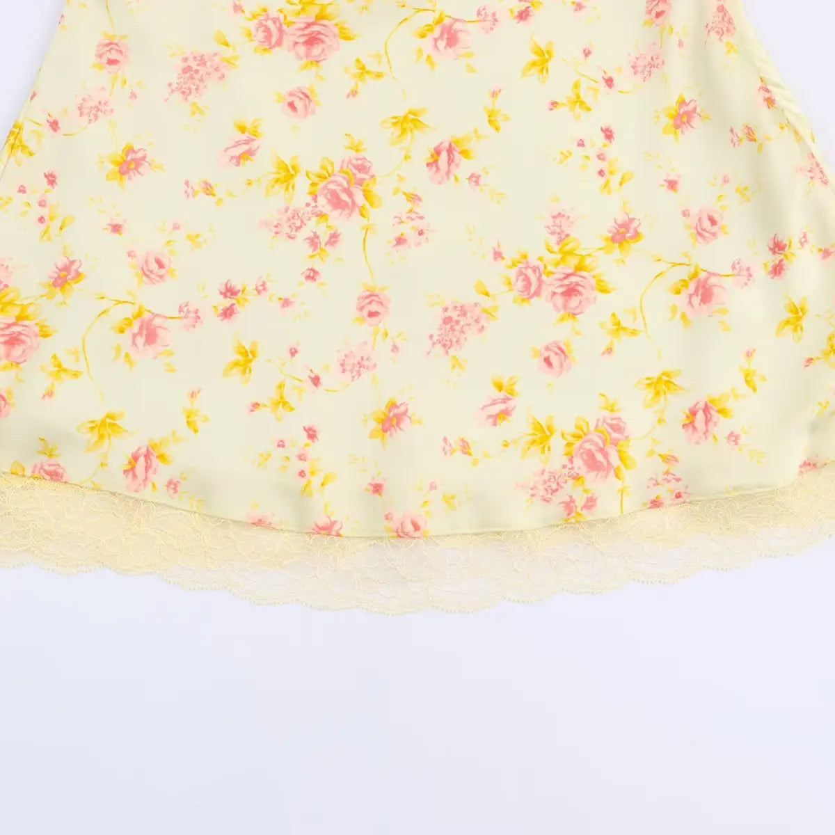 Close-up of the scalloped lace hem on a pale yellow floral dress, showing the delicate lace trim.