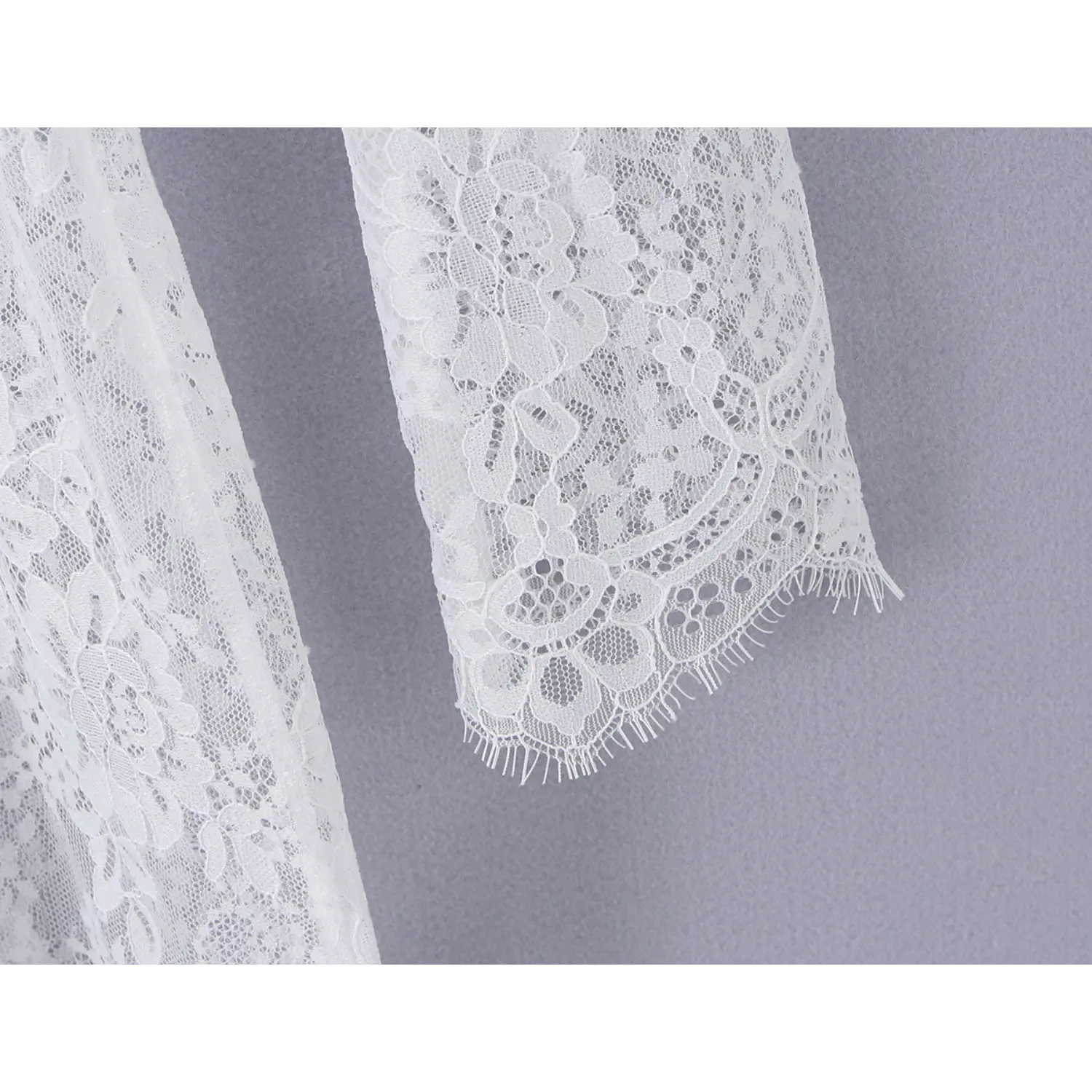 Close‑up of scalloped fringe lace cuff on long sleeve of white lace maxi dress