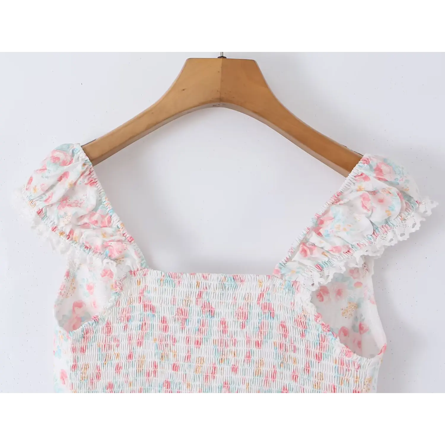 Full upper bodice shot cropped camisole top, elastic gathered ruffle cap sleeves edged with eyelet lace, deep V neck scalloped lace overlay wrap front, vertical fabric button detail, soft pastel watercolor ditsy floral print