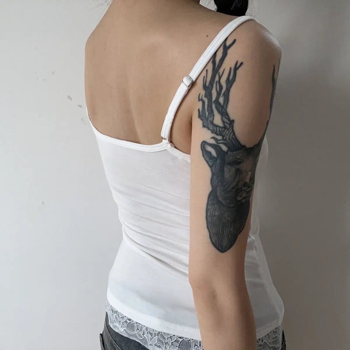 Back view of a white ribbed cami top, showing the adjustable strap and lace-trimmed hem.