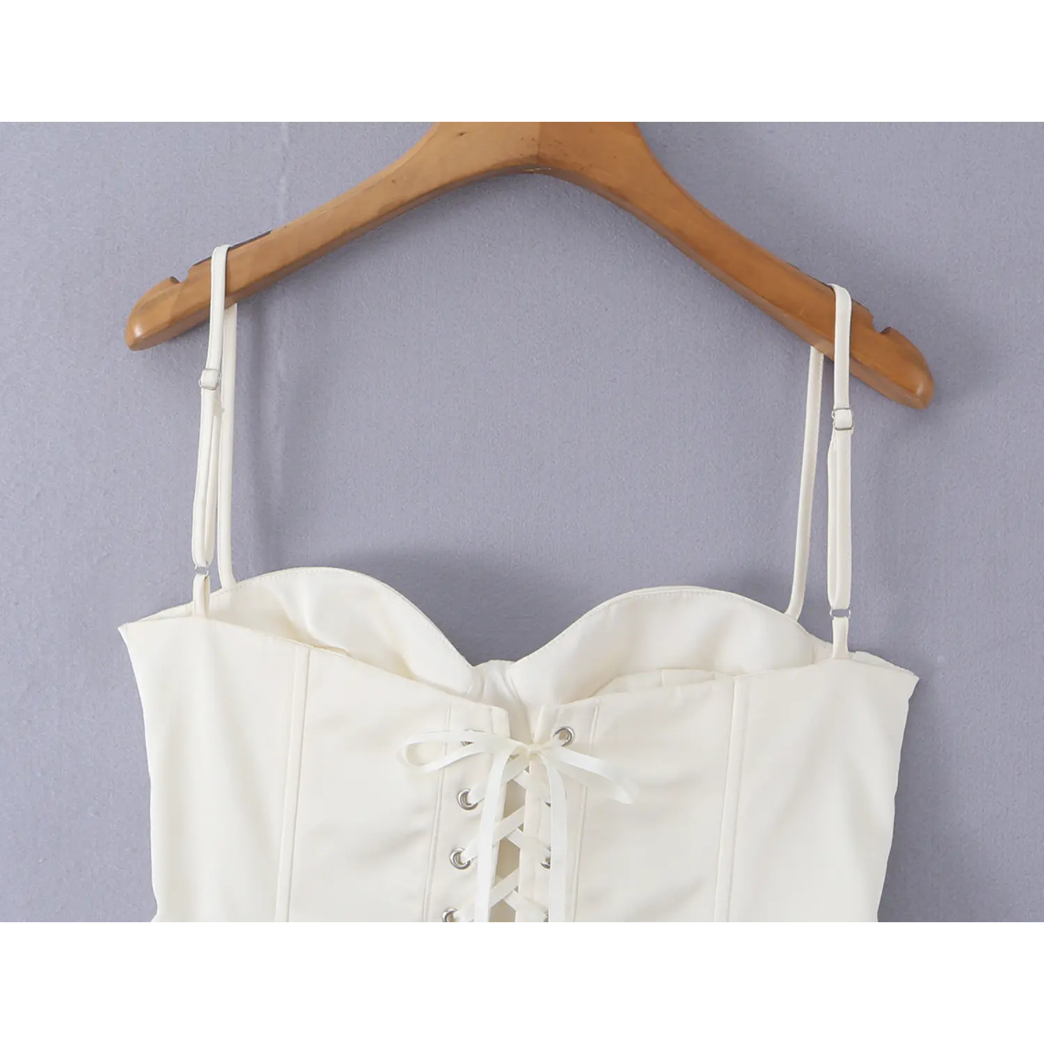 Close-up of ribbon lace-up back closure with metal eyelets on white satin corset camisole top