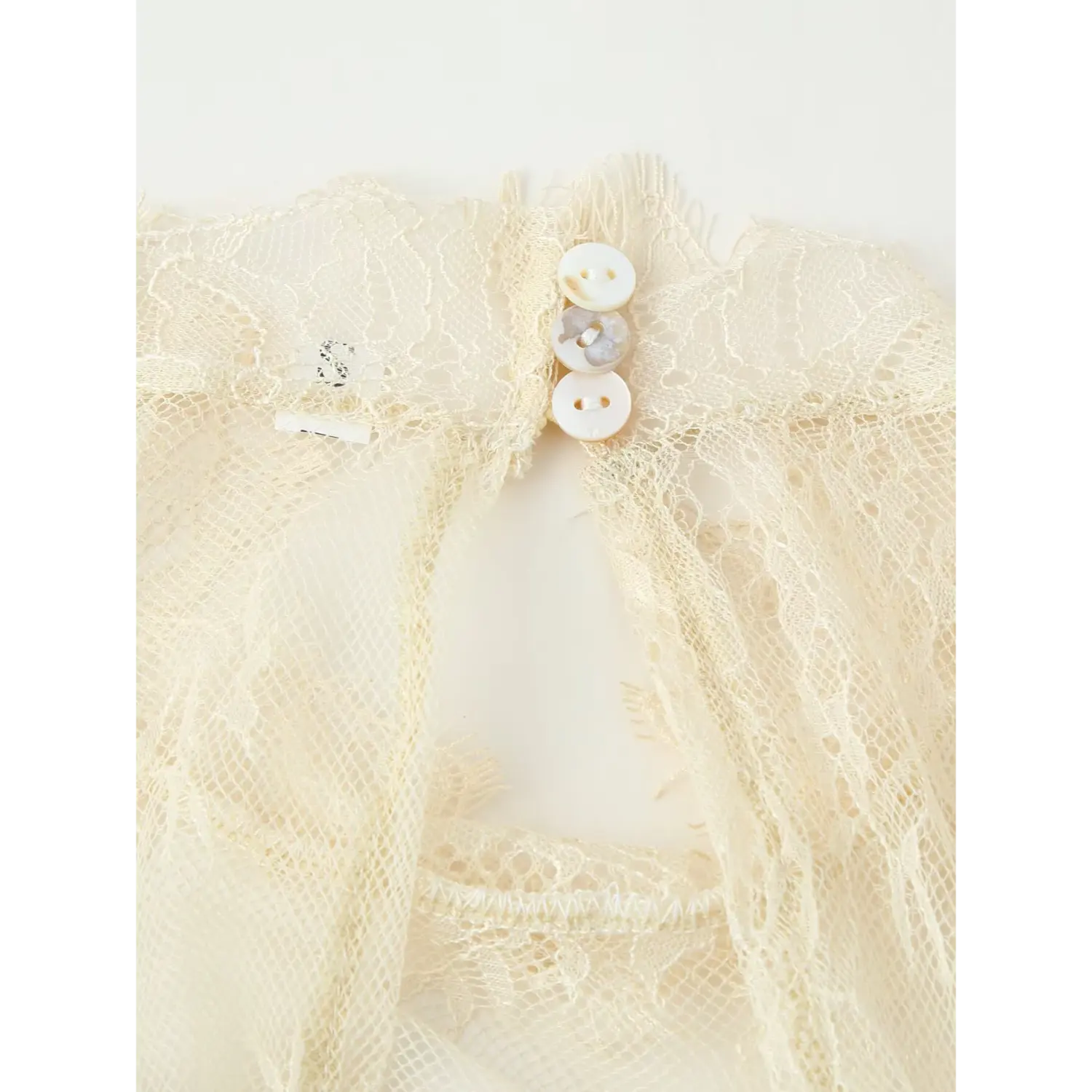 Back neck keyhole close‑up with shell buttons on cream floral sheer lace overlay dress