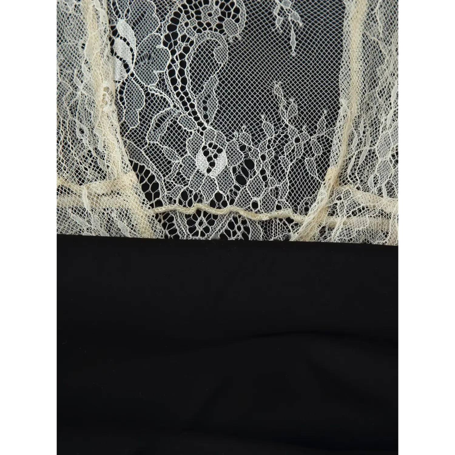 Fabric close‑up showing junction between cream sheer lace overlay and black satin slip dress waist
