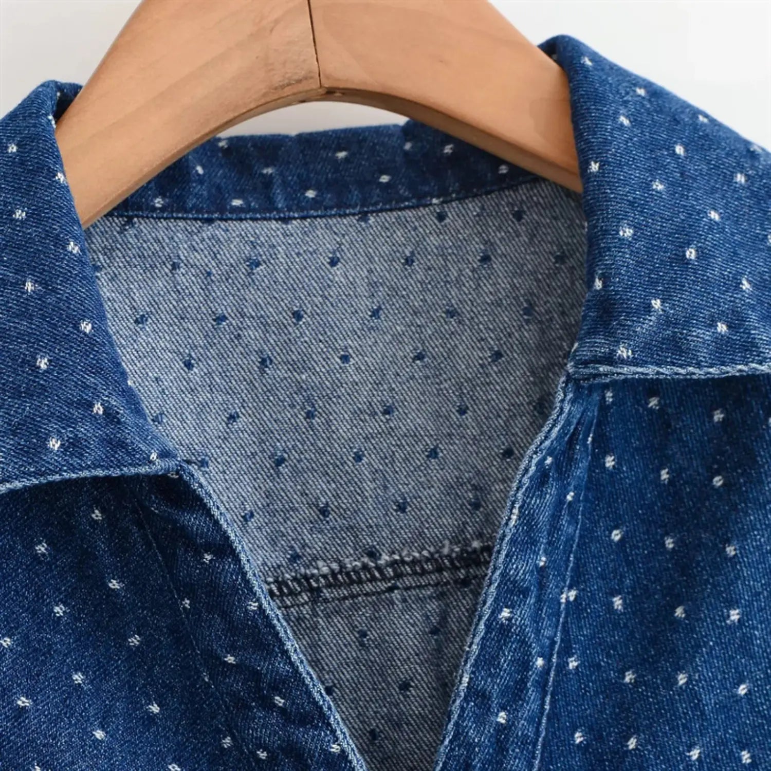 Extreme close-up of collar inner lining, folded neck binding, twill denim weave, tiny white polka dot printing on reverse fabric