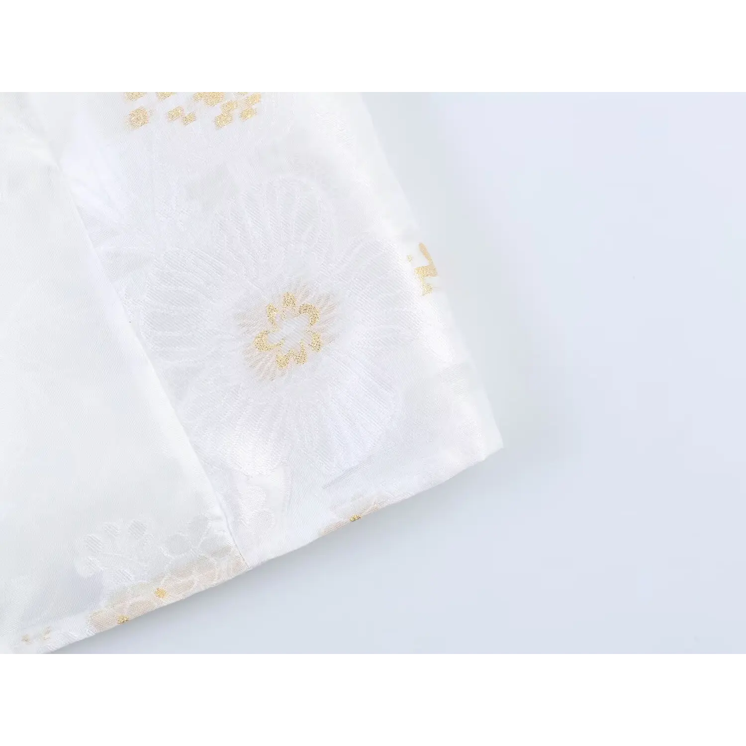 Oversized woven jacquard flower motif close-up, center metallic gold embroidery accent, fine woven fabric grain display