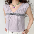 Lifestyle full model shot lavender gray waist bow sleeveless camisole, hidden V neck, vertical pin-tuck pleats, wide cap sleeves, match with white high waist wide leg pants, soft gentle daily casual styling