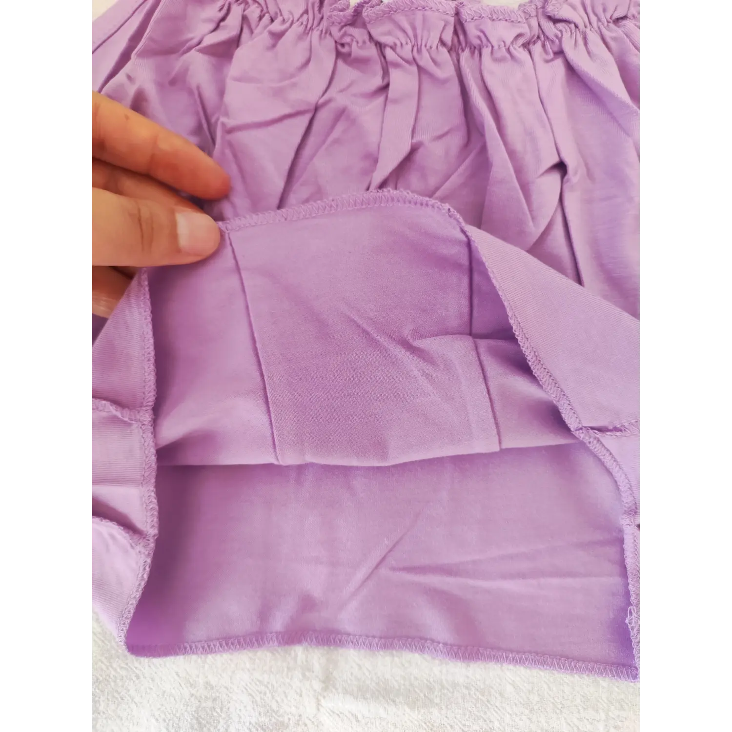 Hand held close‑up inner lining and vertical corset seam hem detail for lavender crop cami