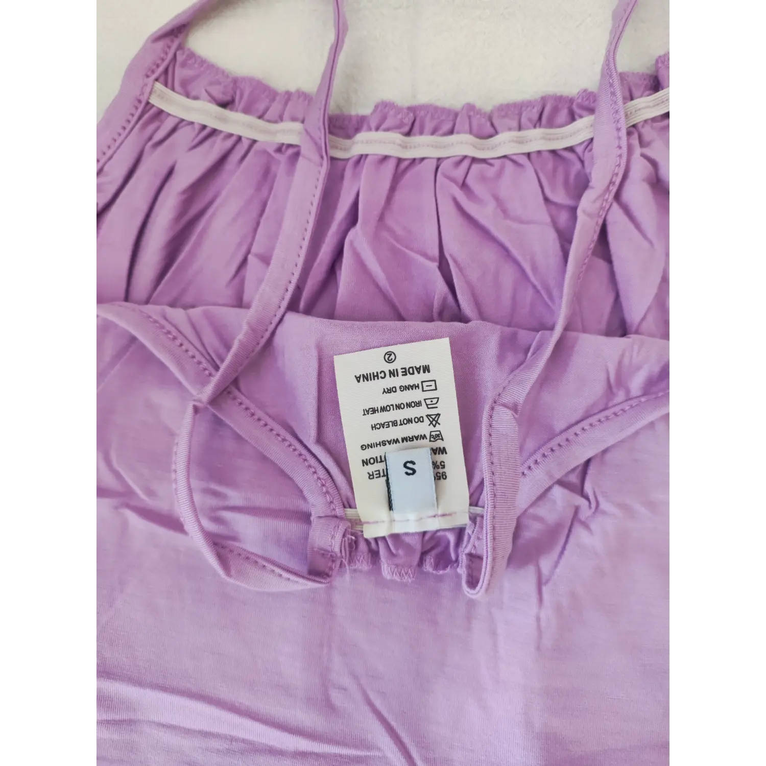 Extreme close‑up inner size and care label tag of lavender ruffle cami crop top