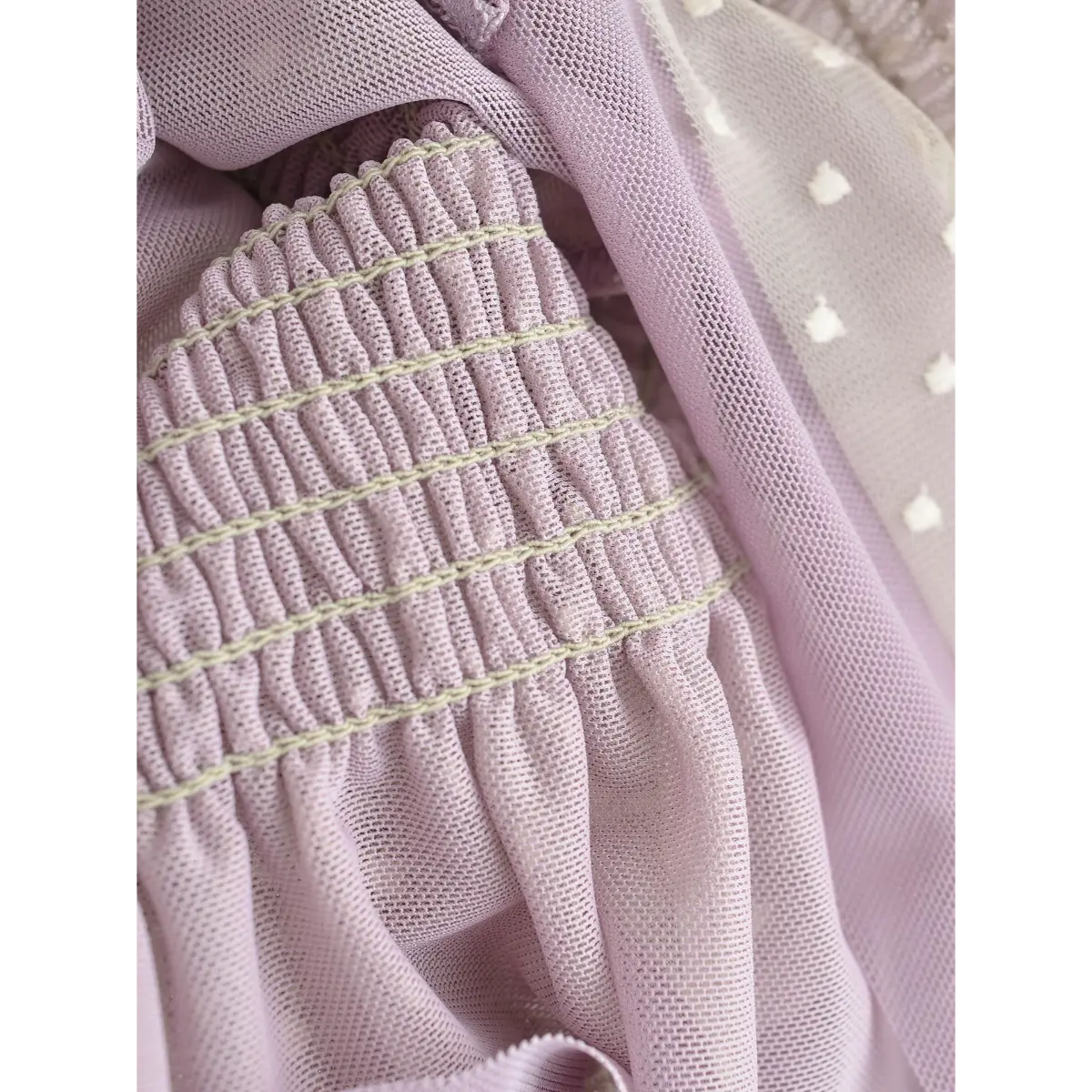 Close-up of the elastic smocking on the back of a lavender heart-mesh camisole.