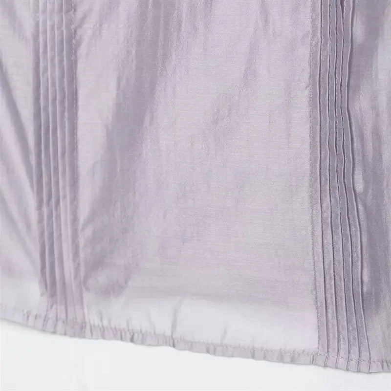 Cropped bottom hem edge closeup, narrow folded finished hem stitching, vertical pin-tuck pleats extend to hem