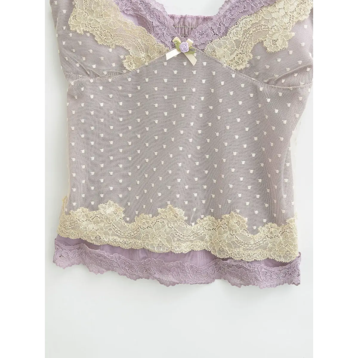 Close-up of the layered lace hem on a lavender heart-mesh camisole.
