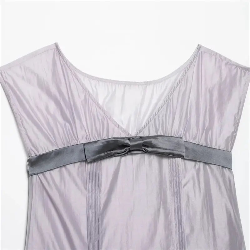 Closeup of front V neck and center waist satin bow, vertical fine pin-tuck pleats down center front, shiny lightweight lavender woven fabric texture
