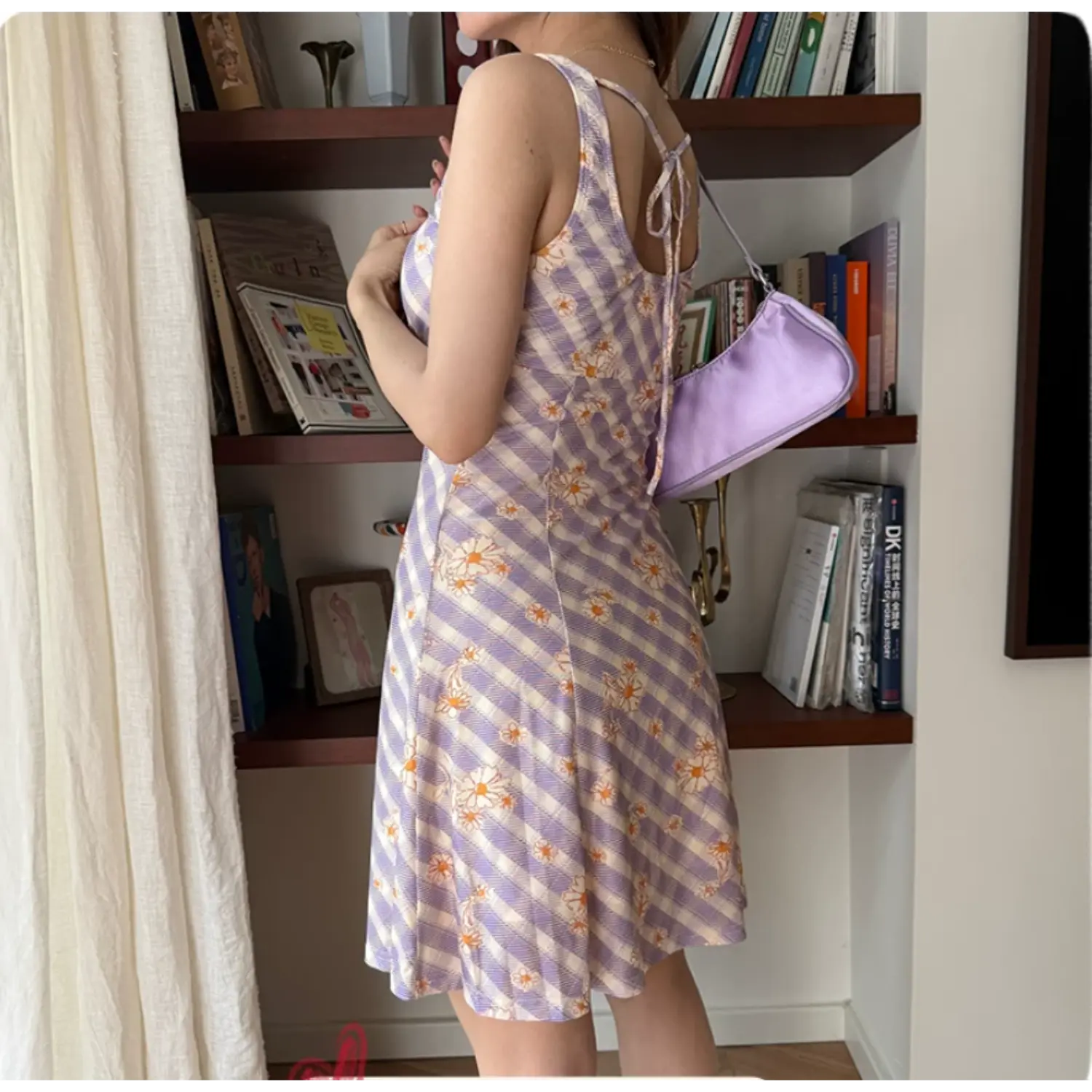 Back view of a woman wearing a lavender and white checkered daisy print slip dress, with a tie-back detail