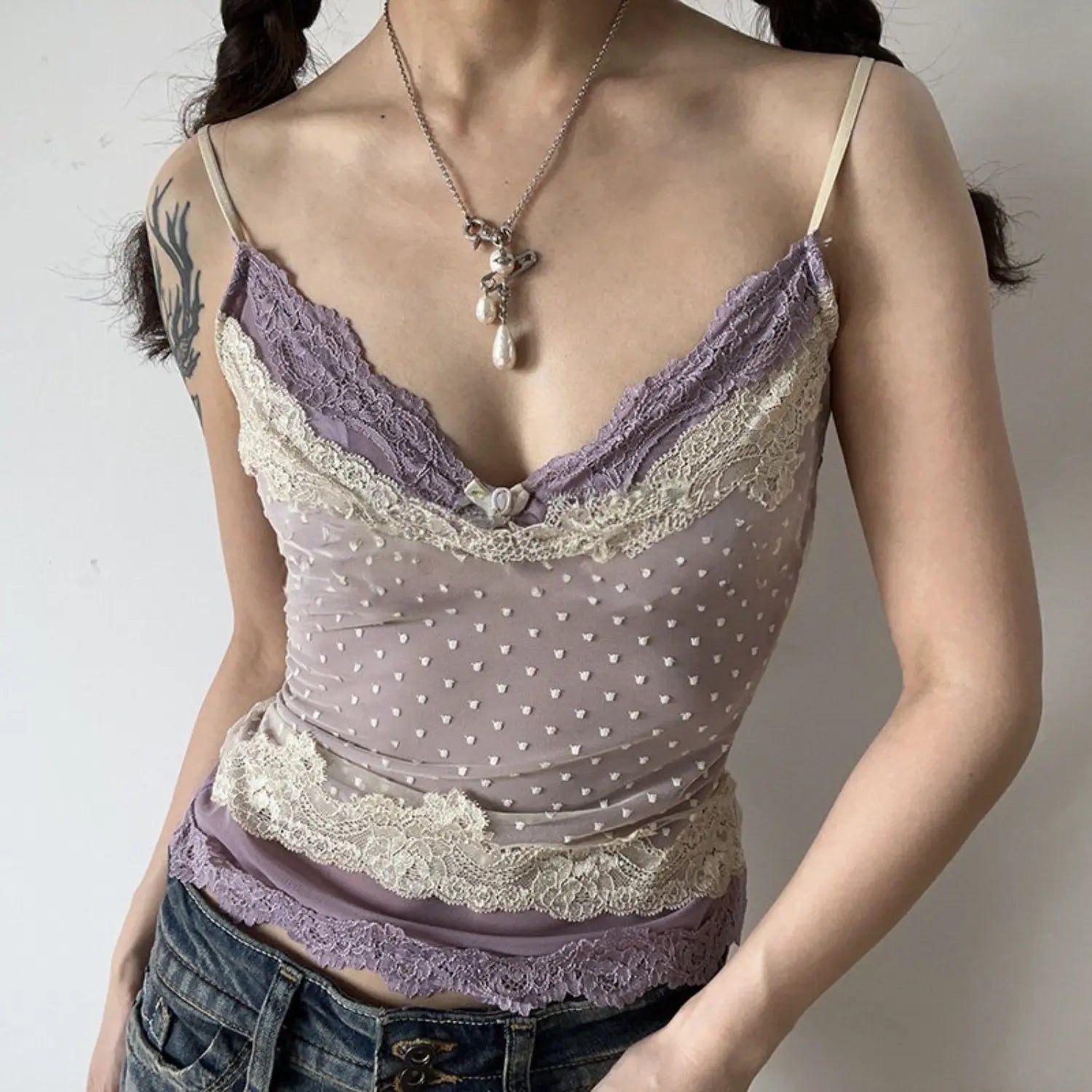 Lavender polka dot double lace cami top half body vibe shot, v-neck contrast lace trim slim cropped fit, layered pearl necklaces soft girly indoor styling