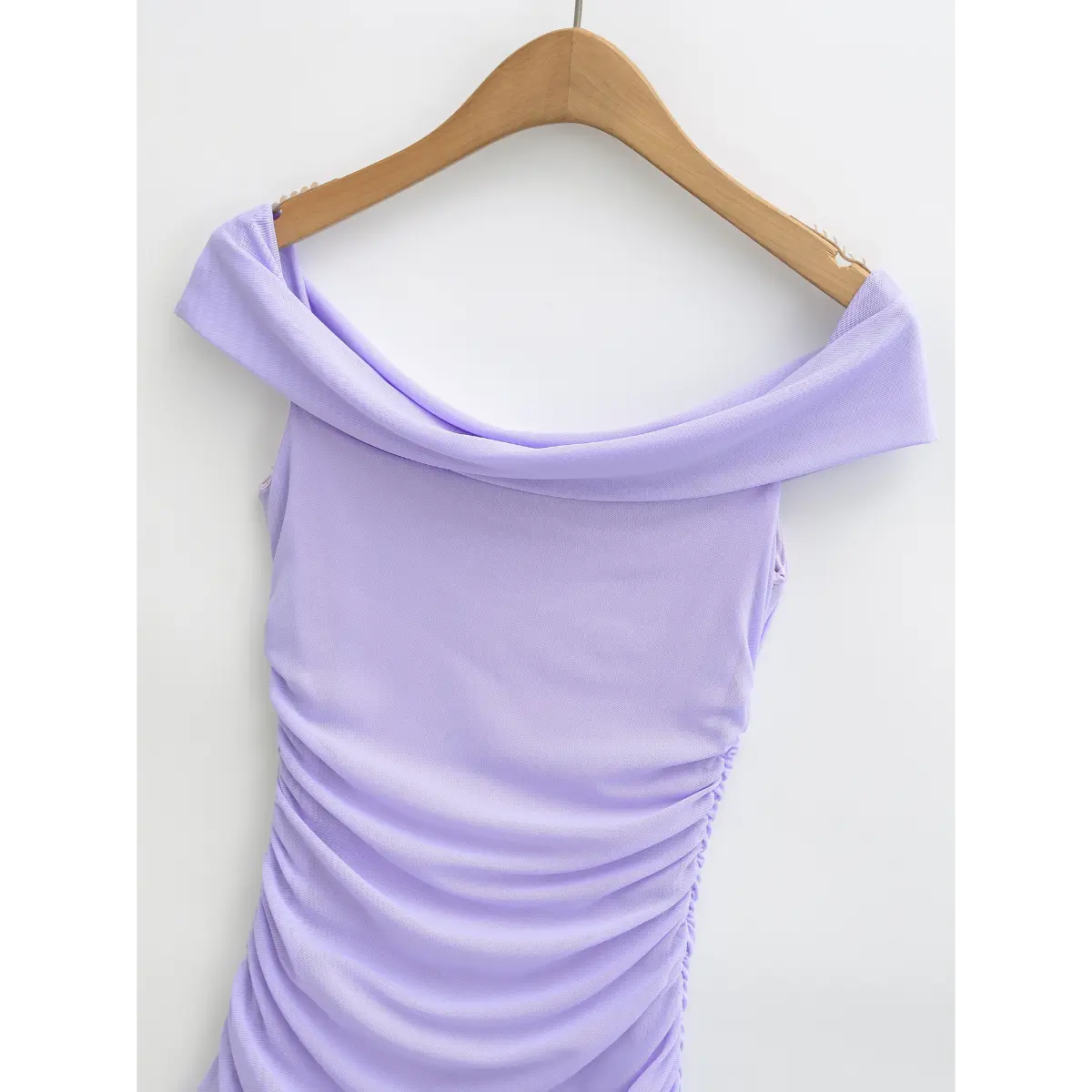 Partial view on wooden hanger showing the draped off-the-shoulder neckline of the lavender dress