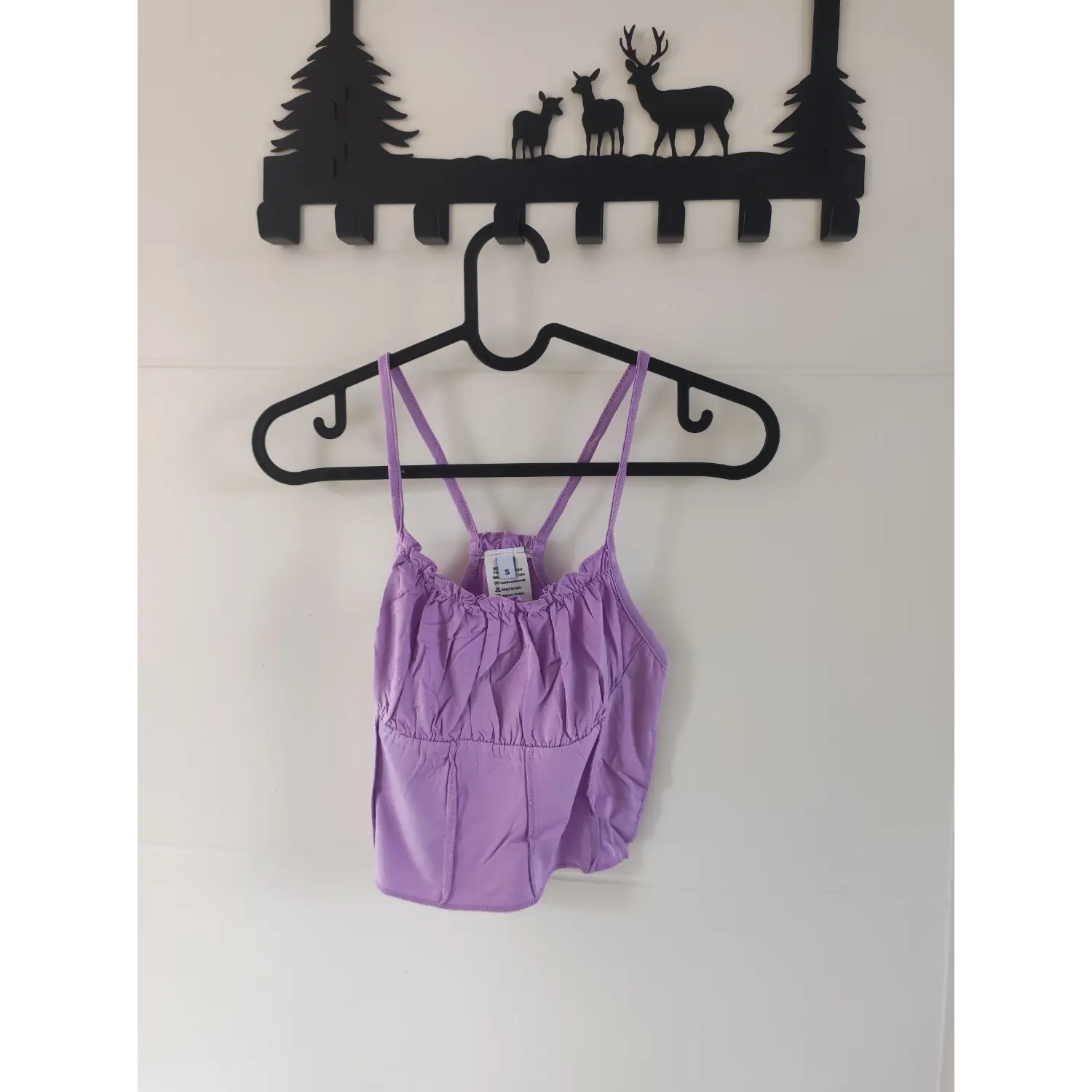 Full front hanging shot lavender ruffle trim cami crop top on plastic hanger against white wall