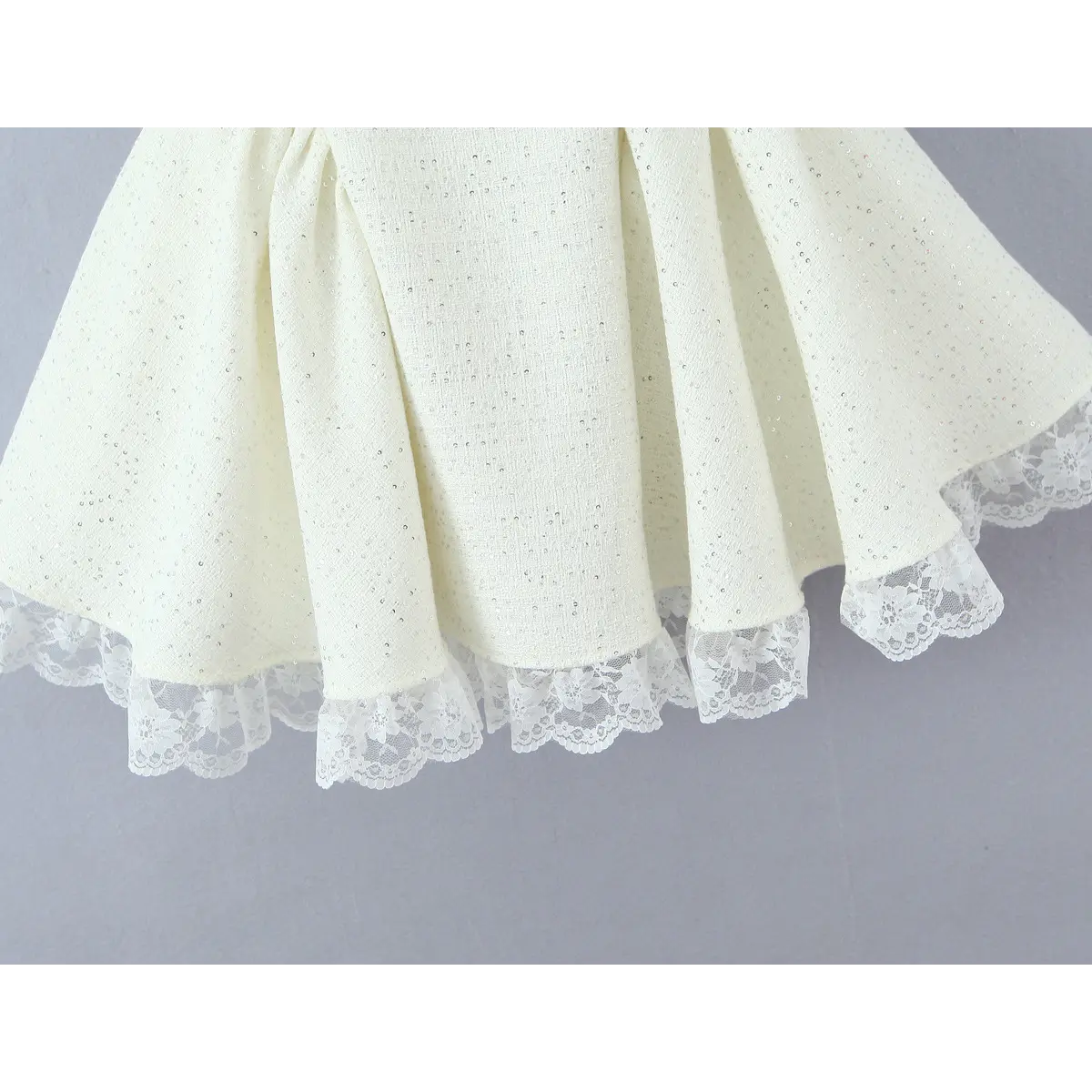 Bottom hem close, multi-layer floral lace frill peeking out from tweed skirt edge.