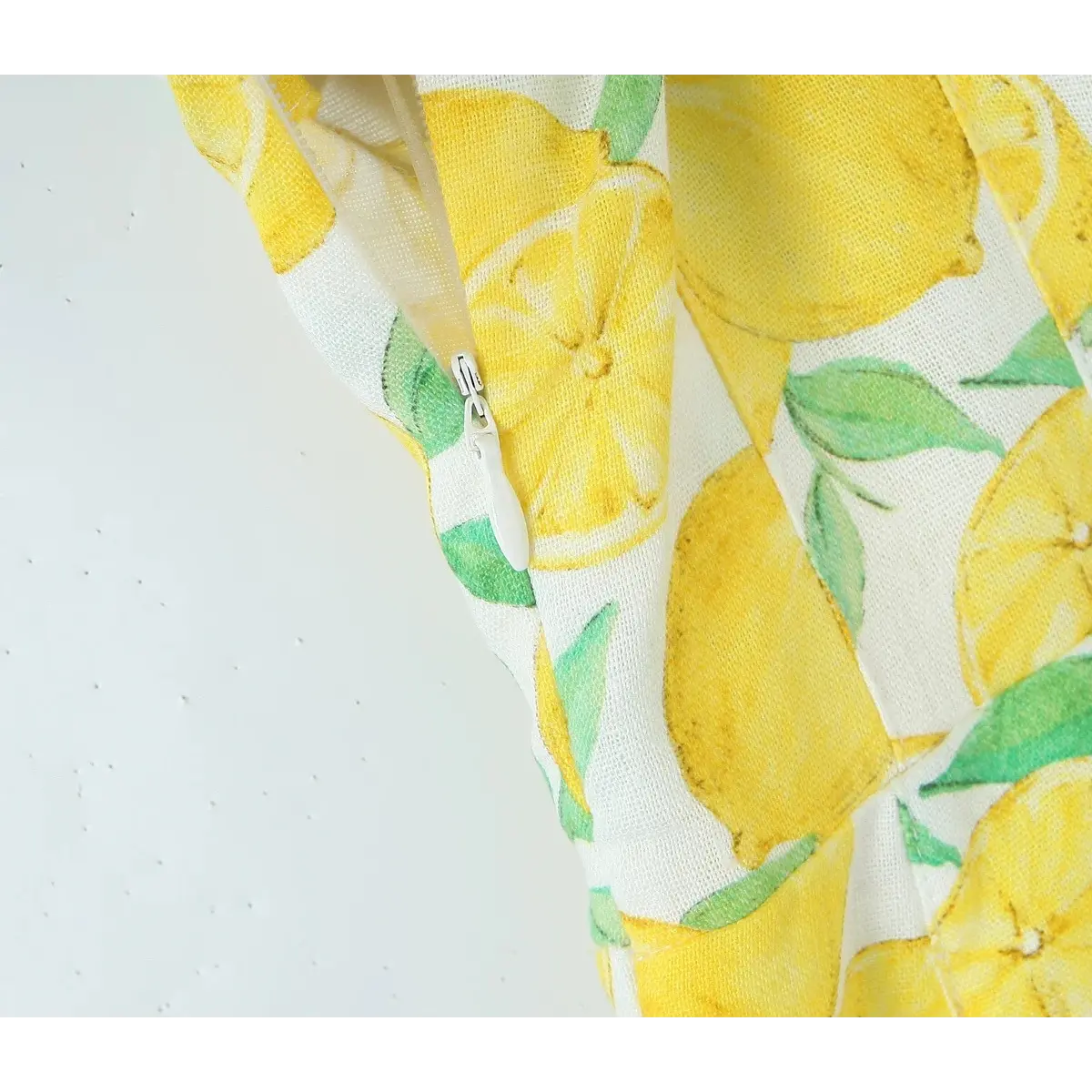Close-up of the hidden side zipper on the lemon print tie-strap dress.