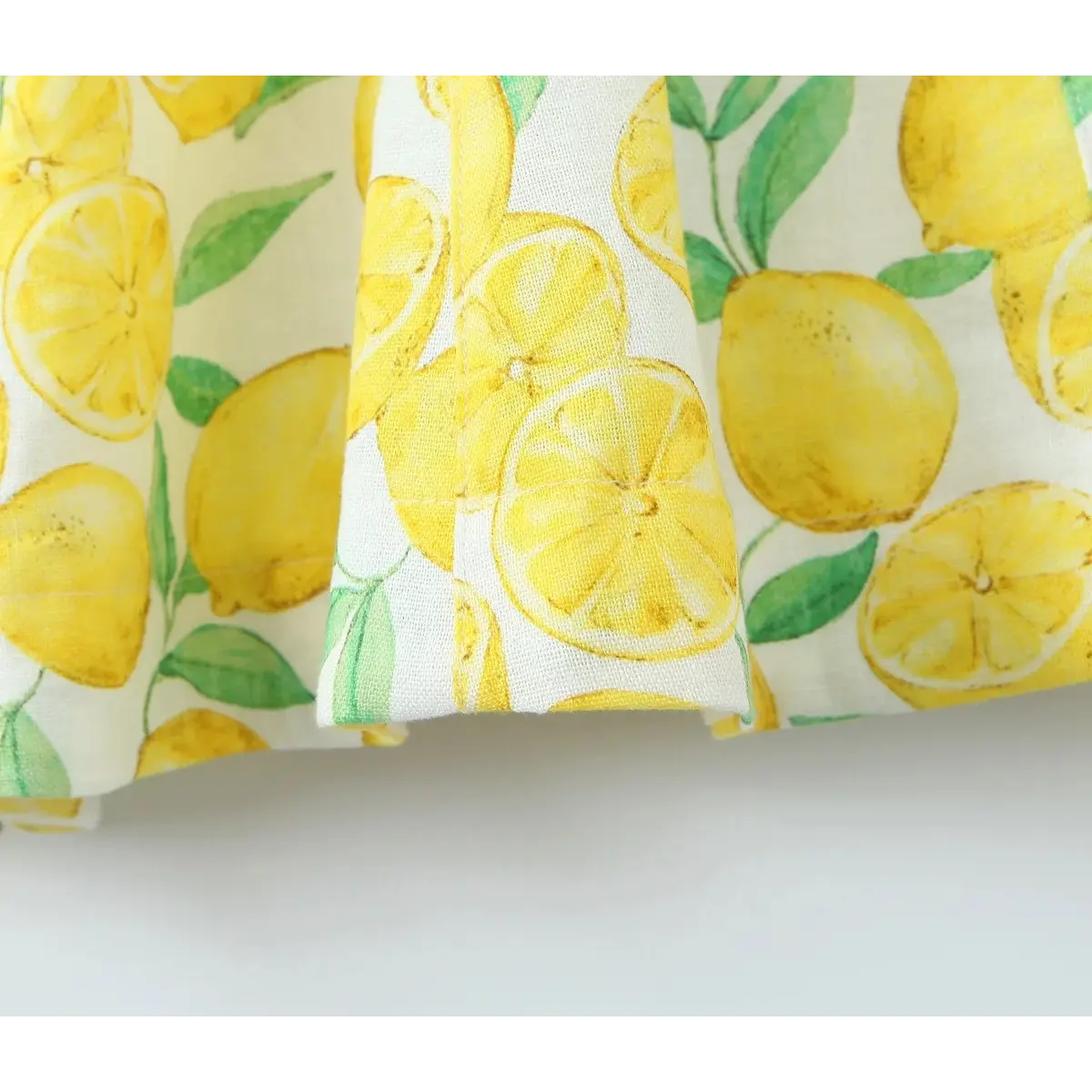 Close-up of the flared skirt hem and watercolor lemon print on the linen-blend dress.