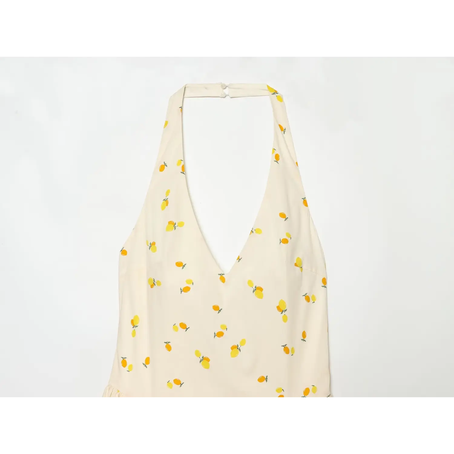 Close-up detail of deep V halter neckline and lemon fabric print
