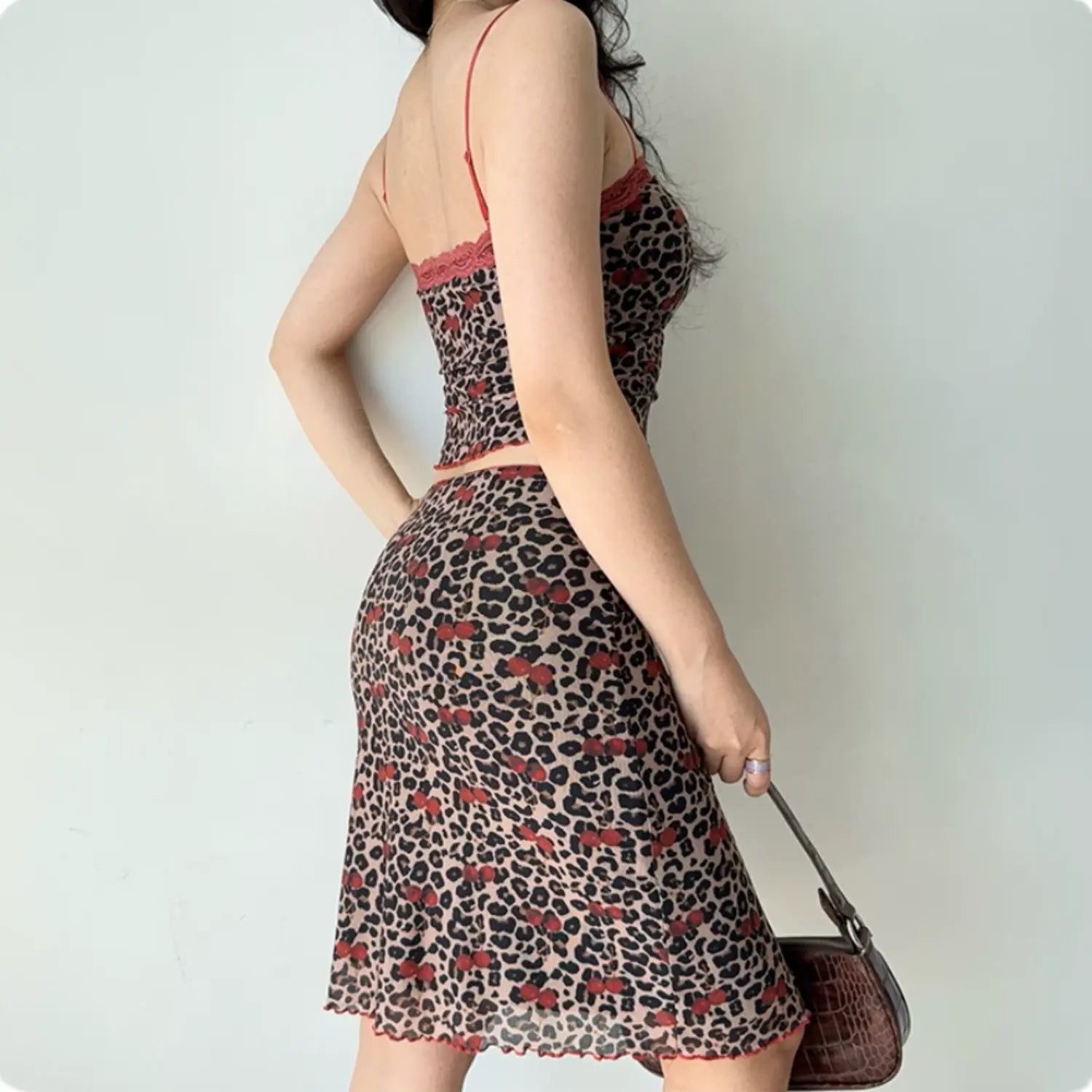 Back lifestyle shot on model of leopard cherry mesh two piece outfit, lace trim cami top, midi skirt with ruffle hem, adjustable thin straps