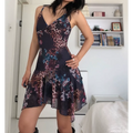 Side view of a woman wearing a form-fitting mesh mini dress with a dark leopard and floral print, showing the fitted bodice and asymmetrical ruffled hem.
