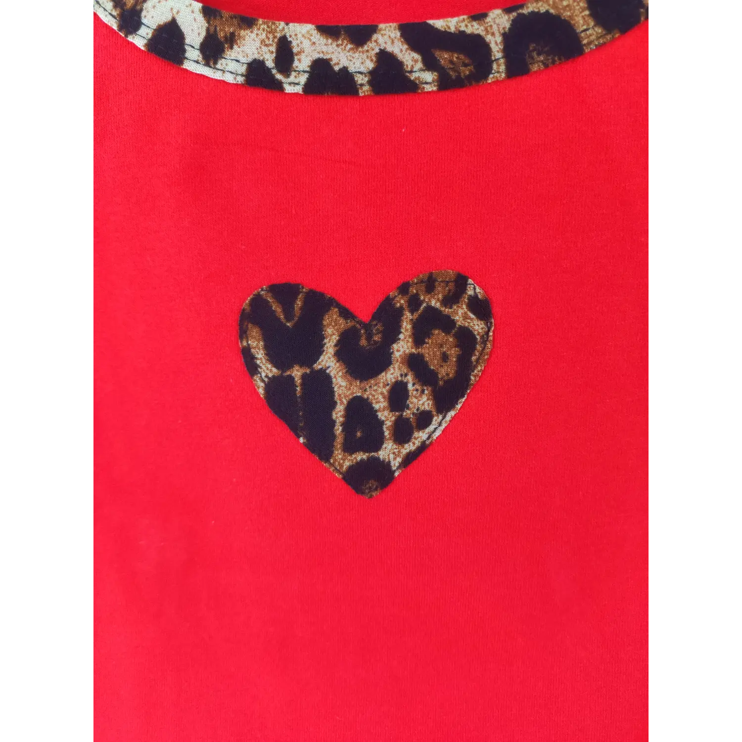 Close-up fabric shot, leopard print heart patch on red crop tank top