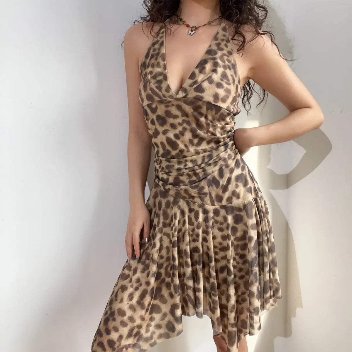 Model wearing a leopard print halter neck midi dress, featuring a deep V-neck, ruched waist, and asymmetrical flowy hem.