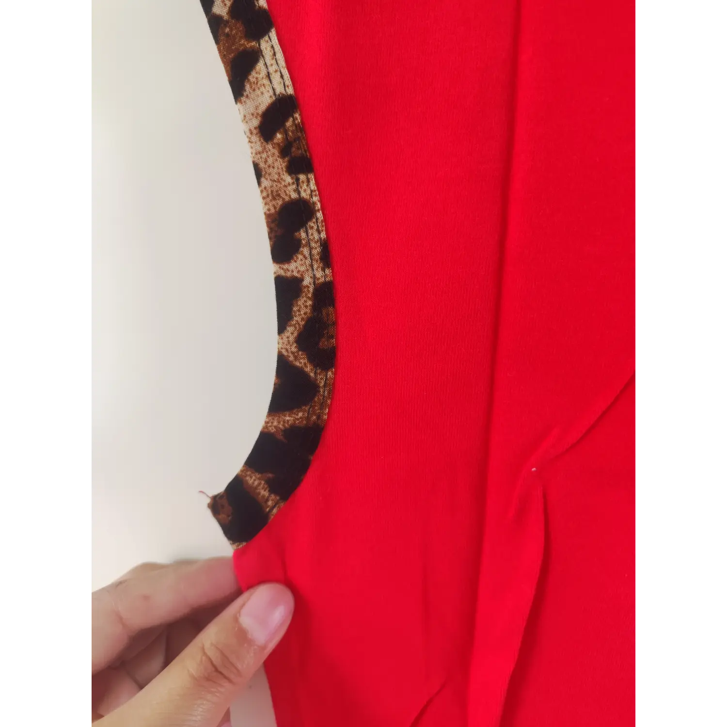 Close-up detail, leopard fabric binding on armhole of red cropped tank top