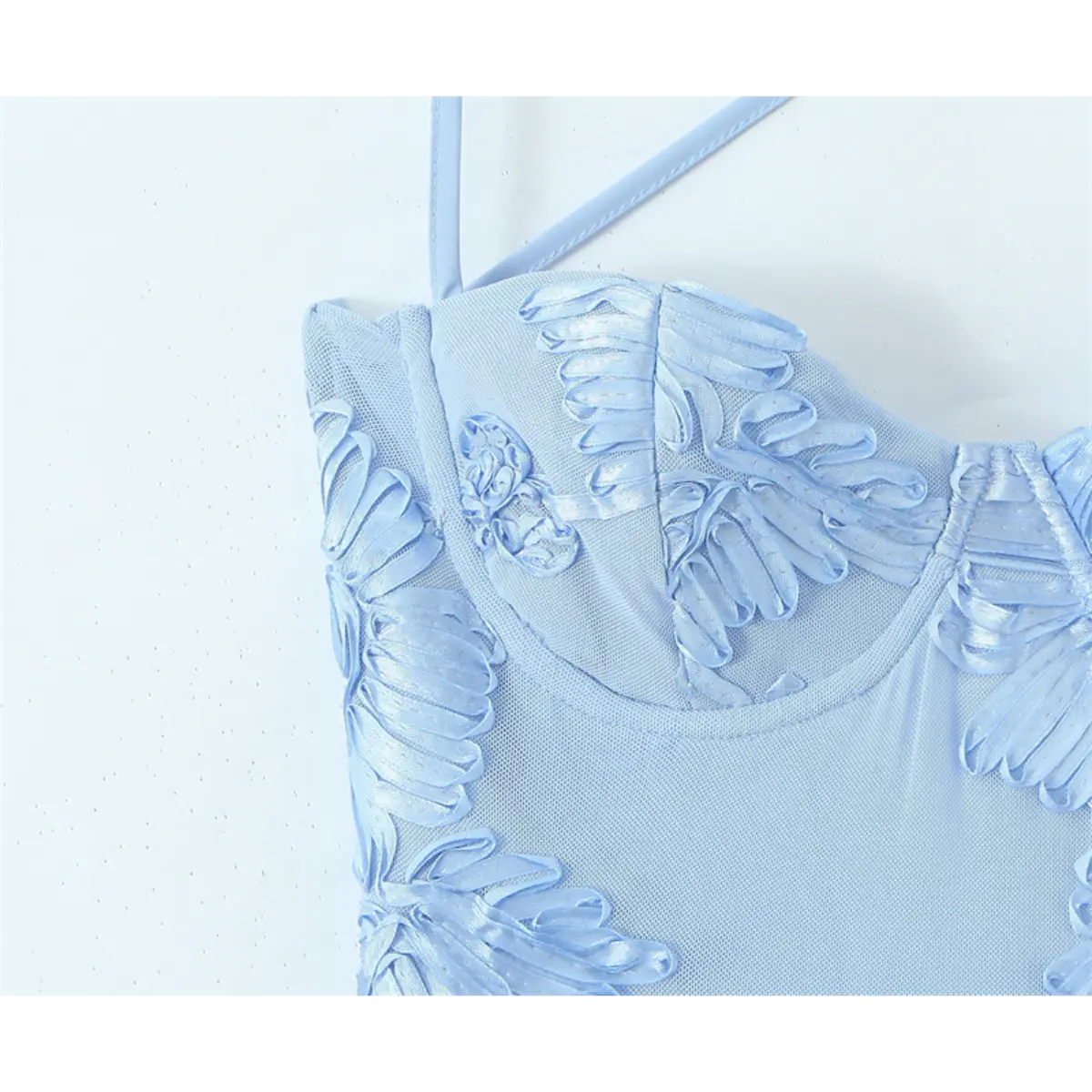 Close-up of the sweetheart bustier on a light blue gown, featuring 3D ribbon flower embroidery and thin spaghetti straps.