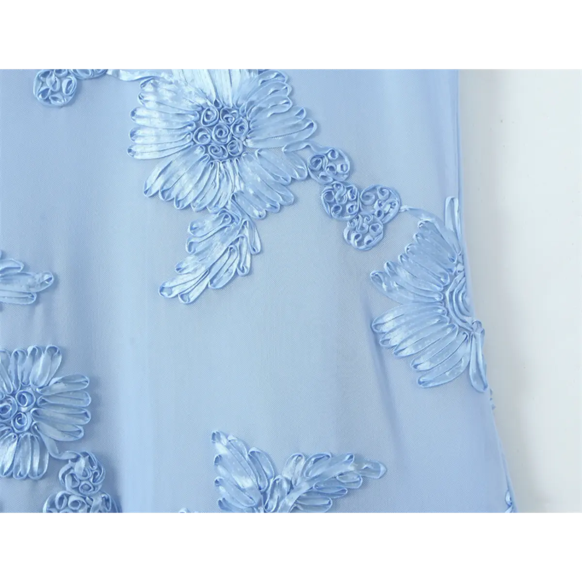 Close-up of the 3D ribbon flower embroidery on a light blue gown, showing the textured floral design and mesh base fabric.