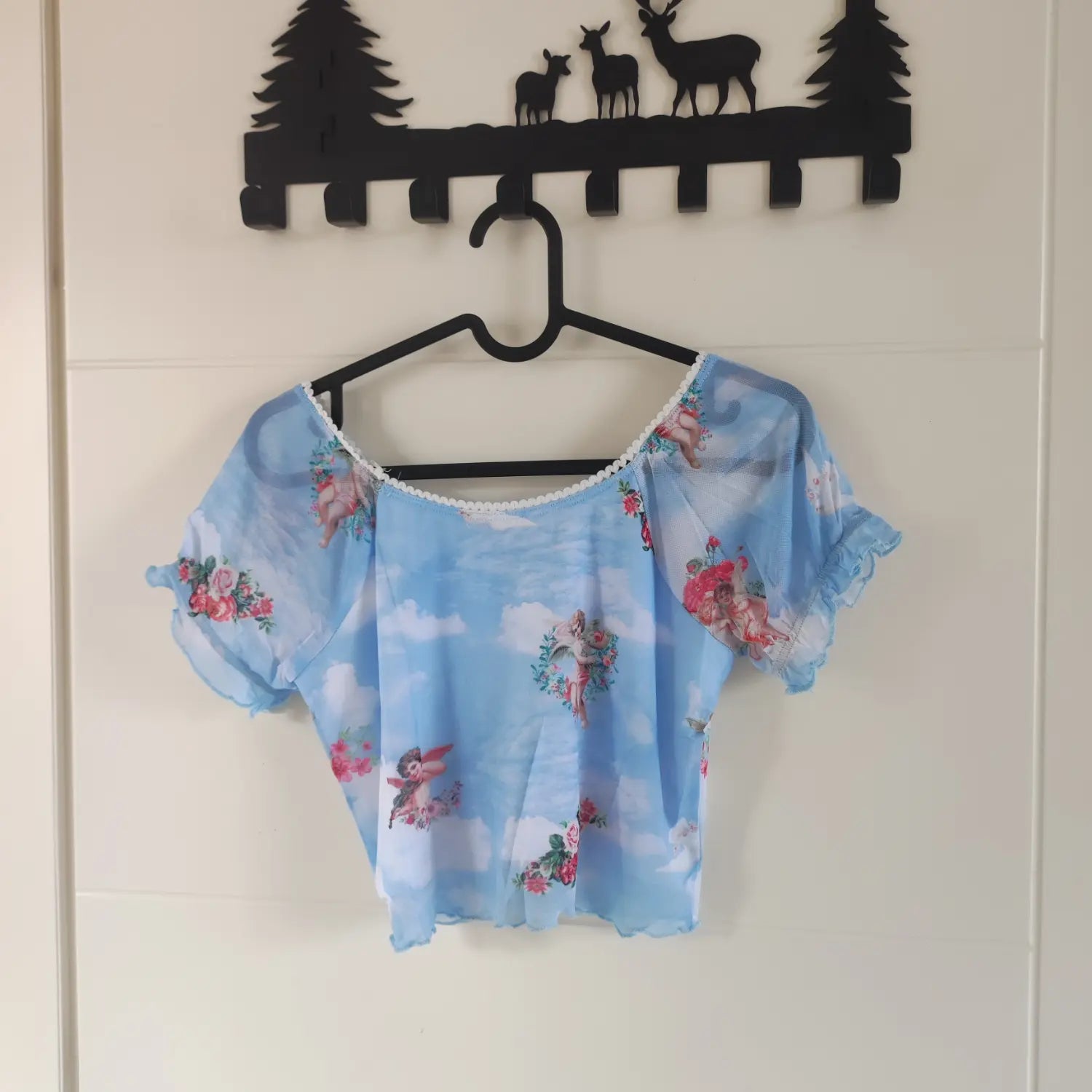 Hanging back view light blue short sleeve mesh crop top cherub floral print on hanger