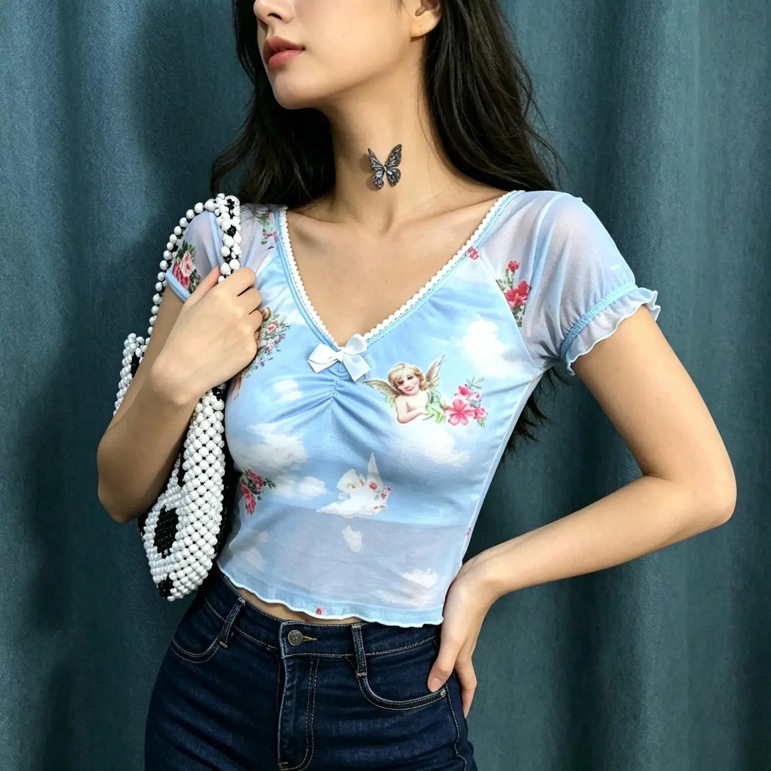 Model side pose shot light blue short sleeve mesh crop top cherub rose print cropped silhouette