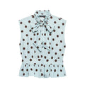 Front flat lay product shot light blue sleeveless blouse, big brown polka dot print, neck self tie bow, smocked waist, ruffle hem, front button placket